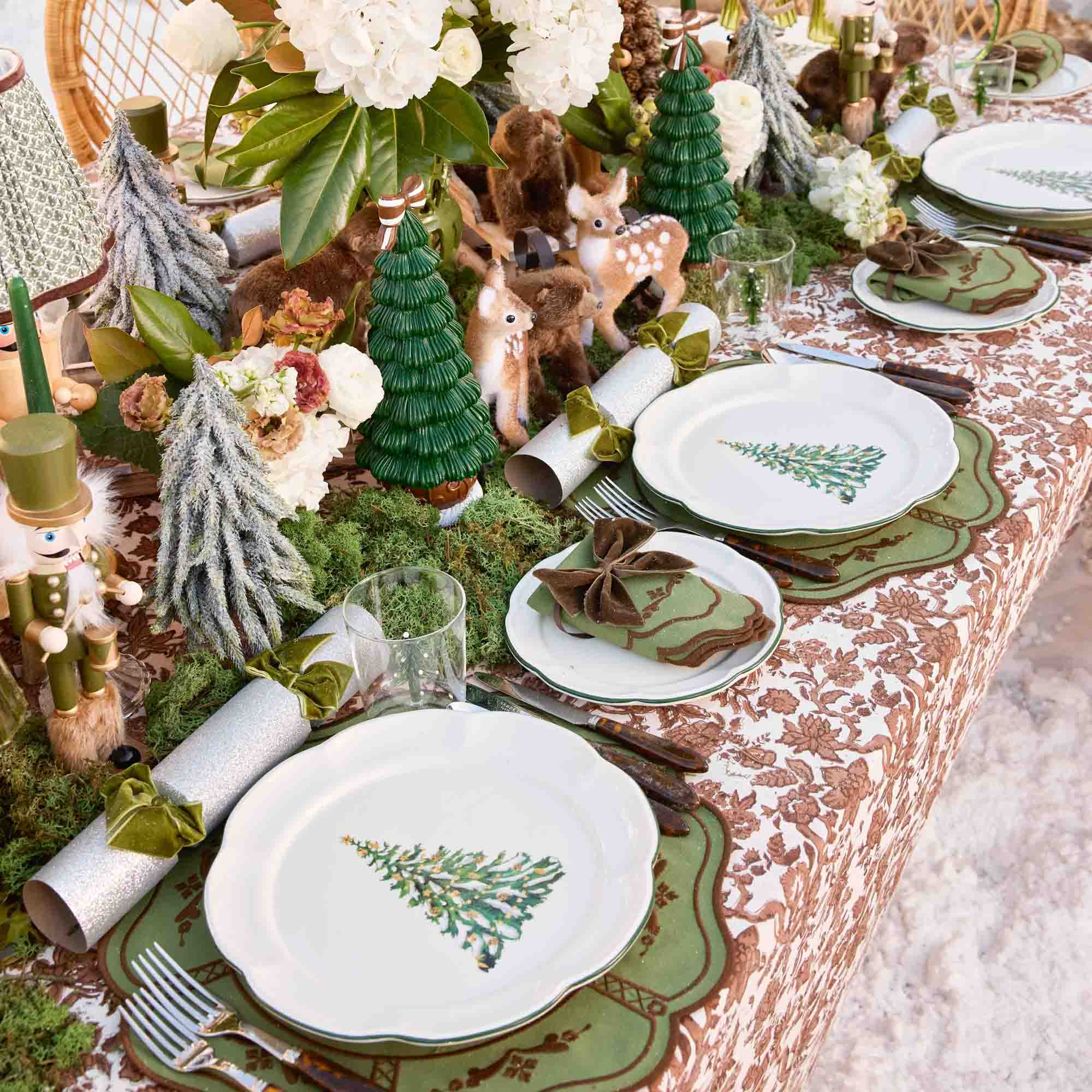 Decorative Christmas table setting with plates, cutlery, and festive decorations on a patterned tablecloth.