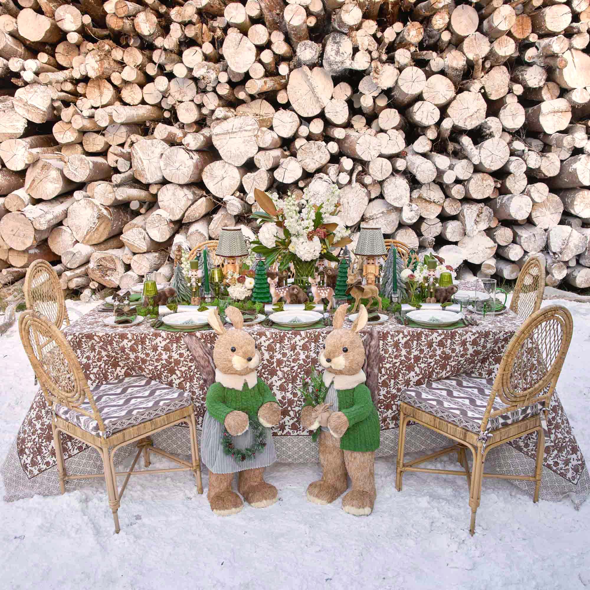 Decorative table setting with teddy bears in front of stacked logs