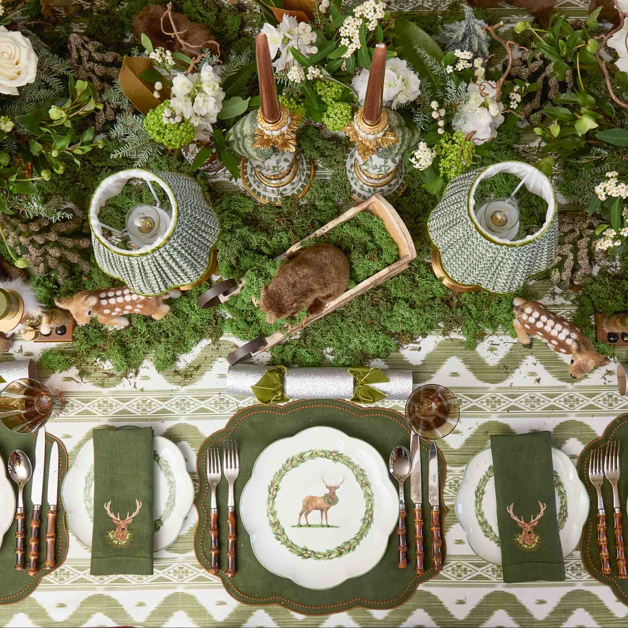 Decorative table setting with green and brown theme, including plates, cutlery, and floral arrangements.