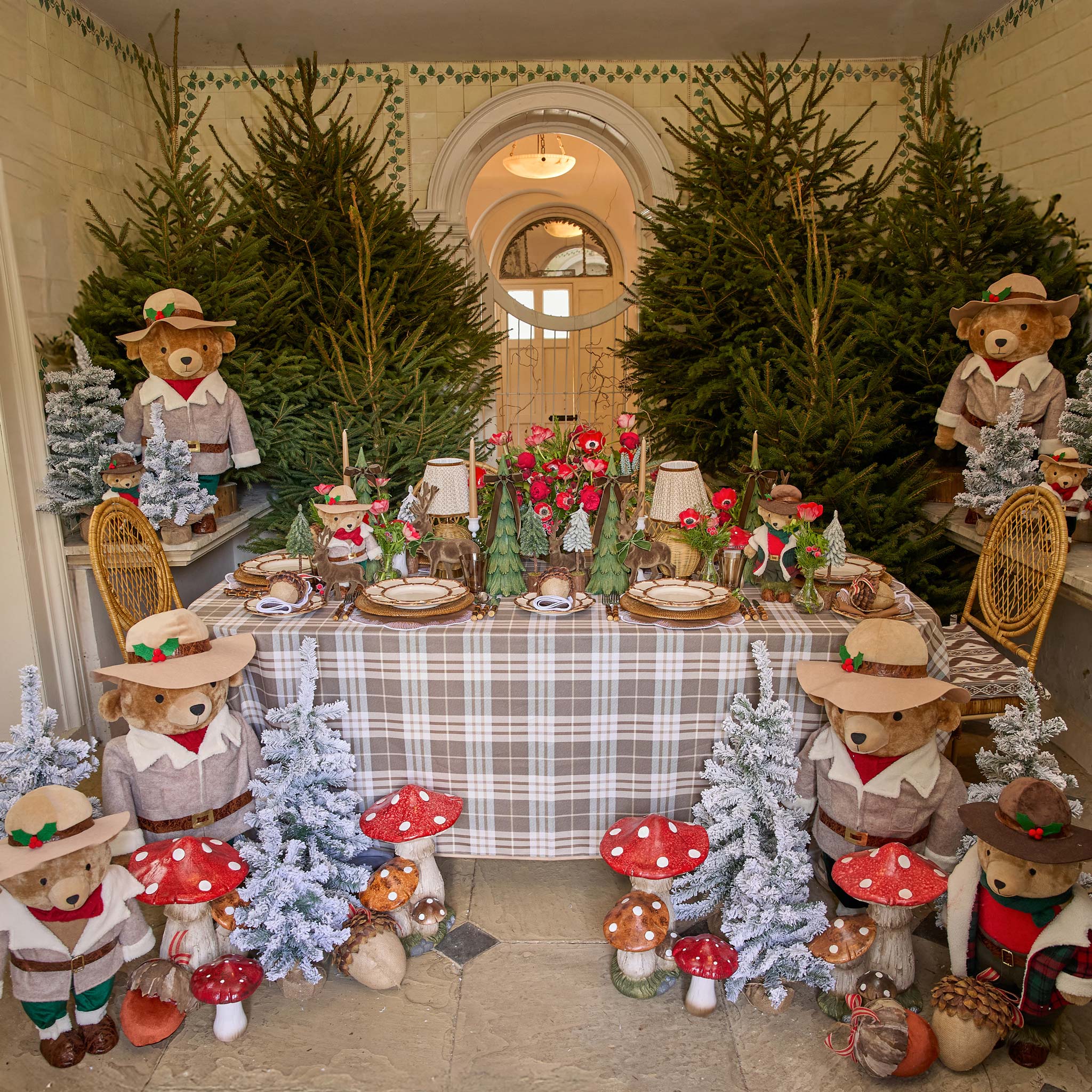 Decorative table setting with teddy bears, Christmas trees, and tableware in a festive room.