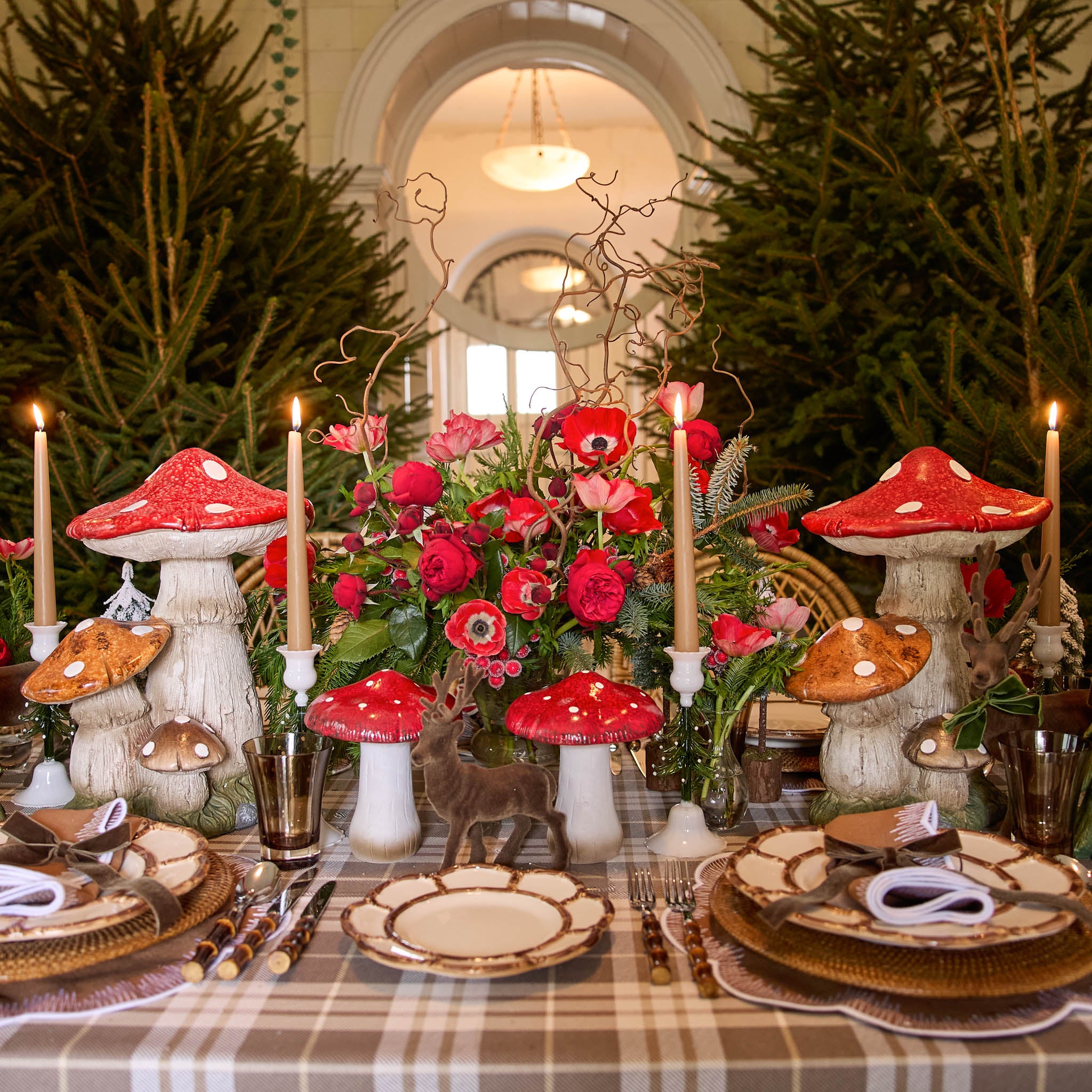 Decorative table setting with red mushroom candles and floral arrangements.