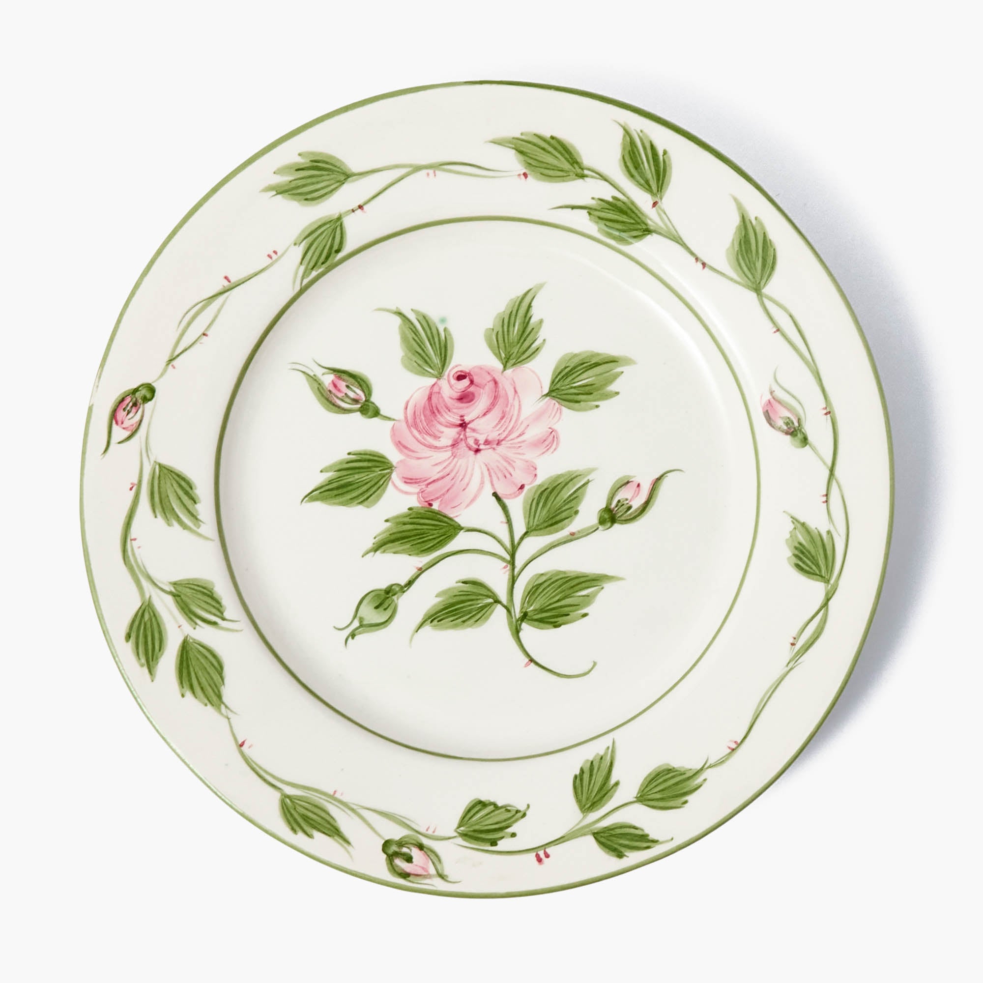 A ceramic dinner plate with a floral pattern, featuring a pink rose in the center and green leaves around the border.
