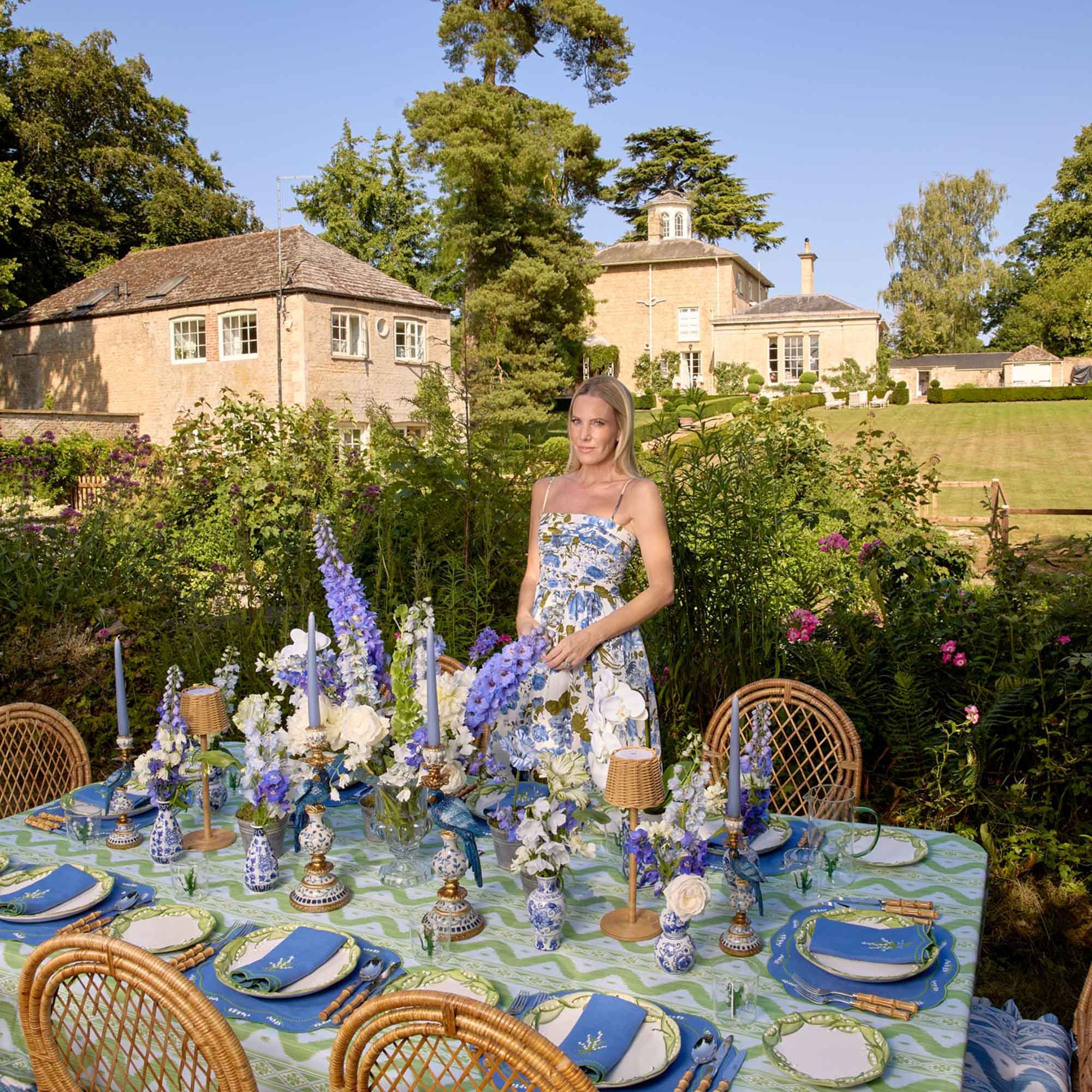 Woman in a garden setting with a decorated table and house in the background