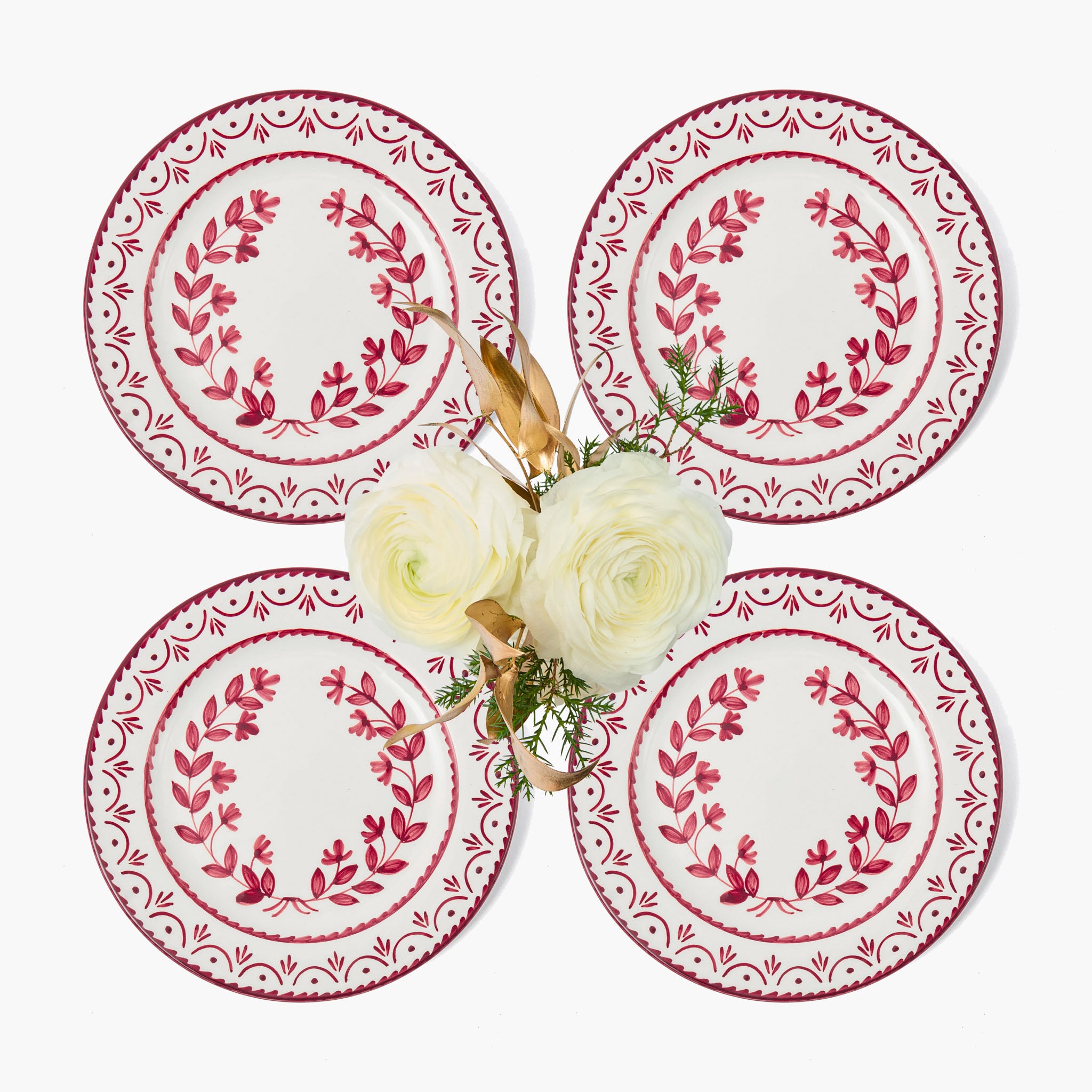 Four decorative plates with red floral patterns on a white background, featuring a small bouquet of flowers.