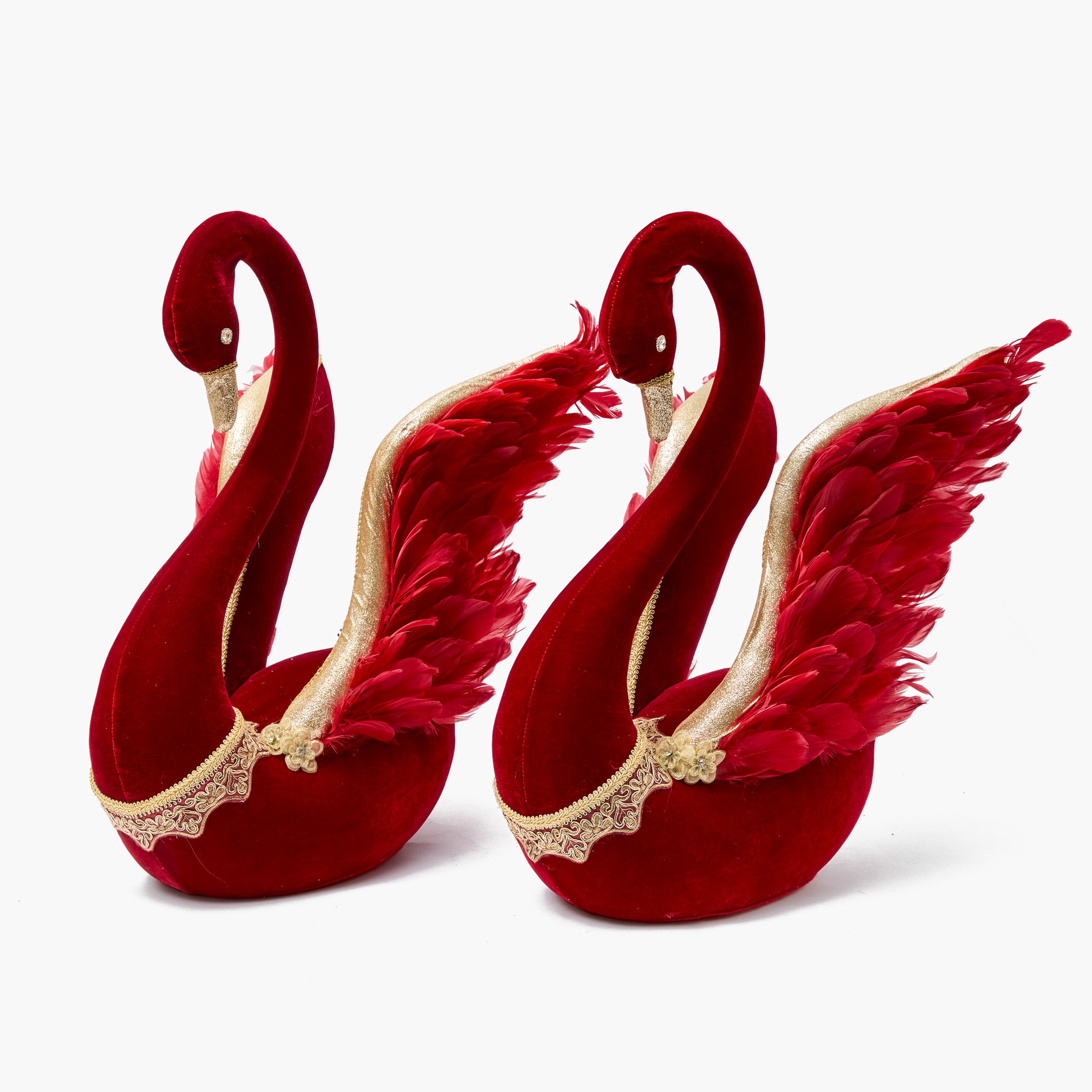 Two red swan-shaped slippers with feather details on a white background