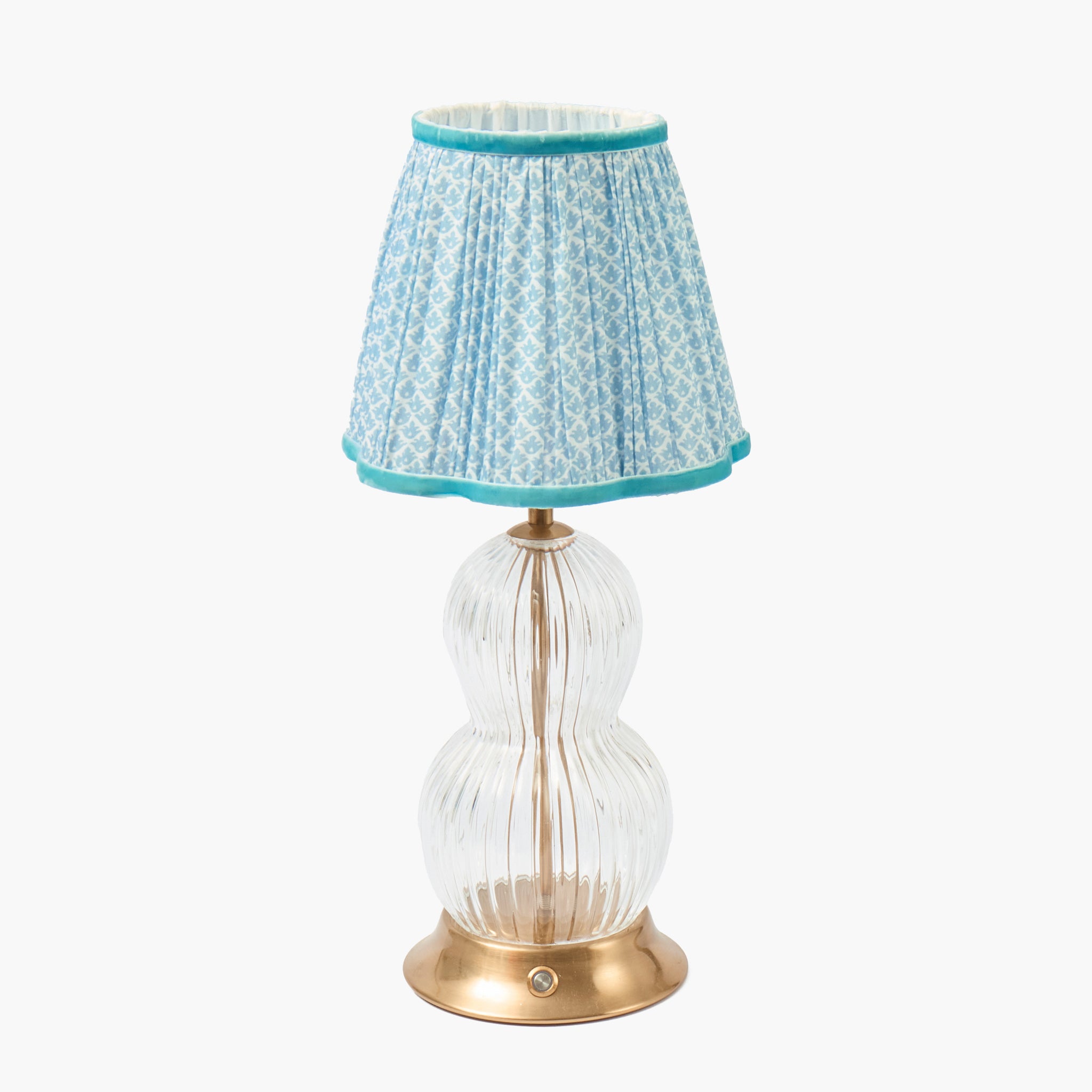 Table lamp with a clear glass base, gold accents, and a blue patterned shade on a white background