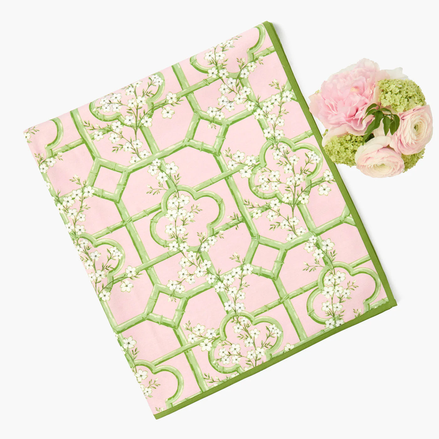 Pink and green patterned fabric with floral design, accompanied by a small bouquet of pink and green flowers.