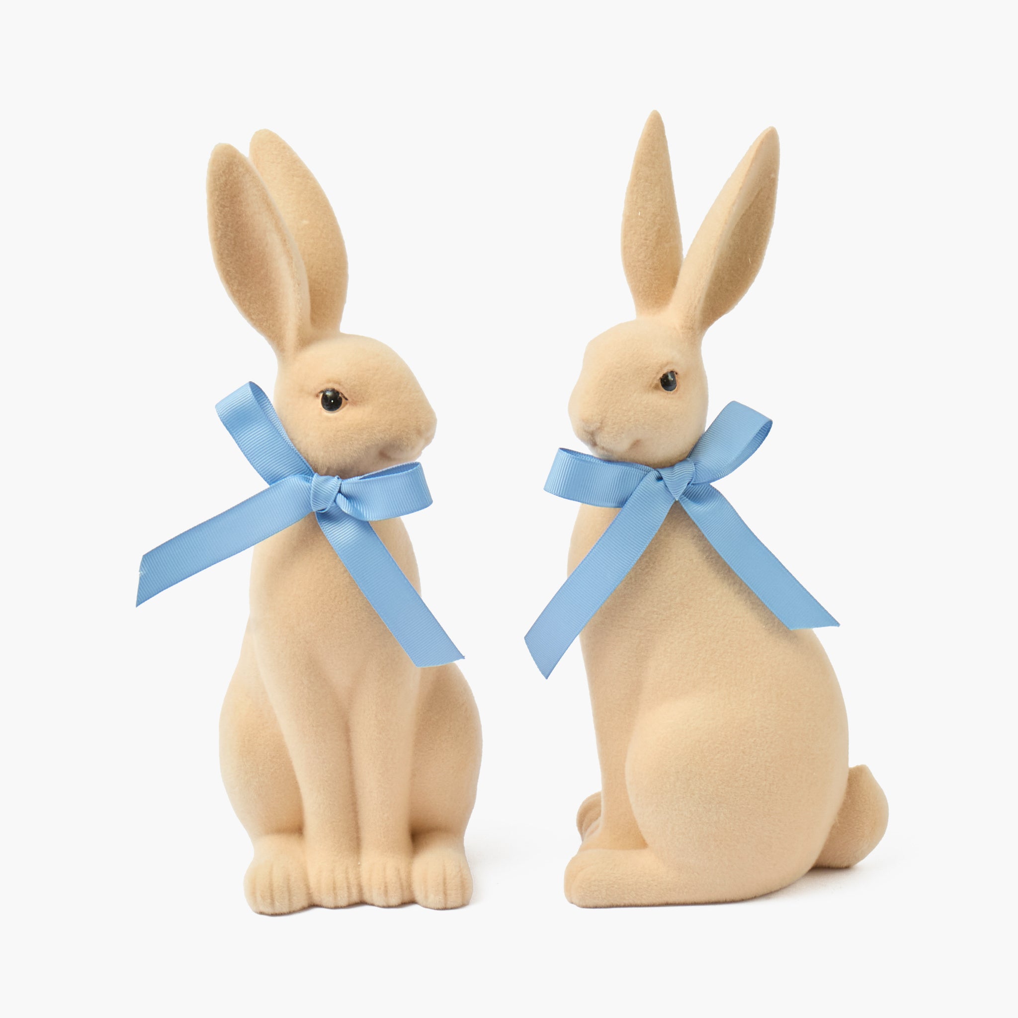 Two rabbit figurines with blue bows on a white background