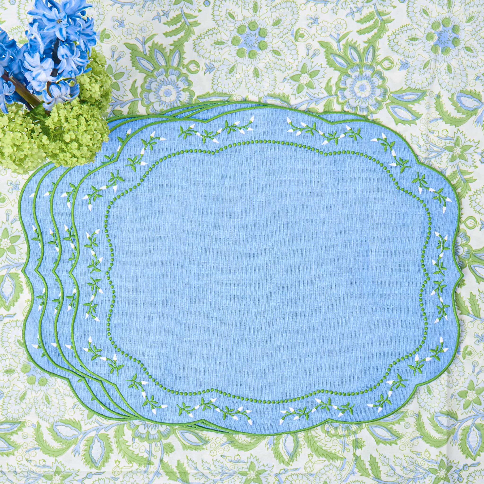 Set of blue placemats with green floral border on a floral background