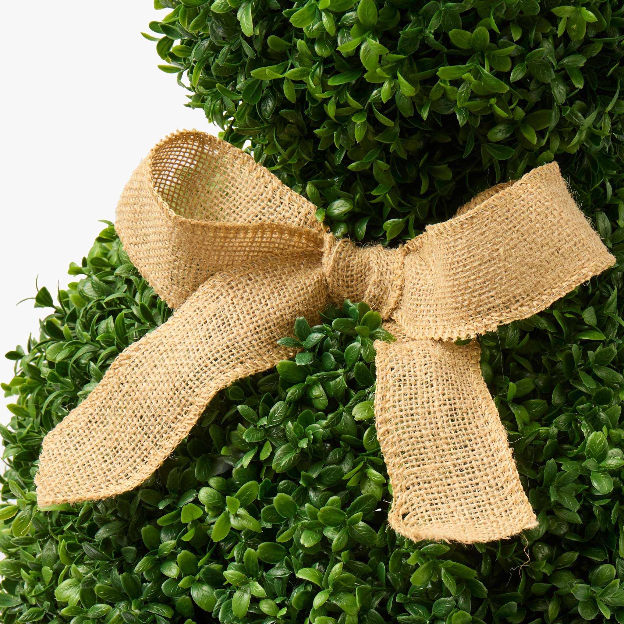 Artificial boxwood wreath with a burlap bow on a white background