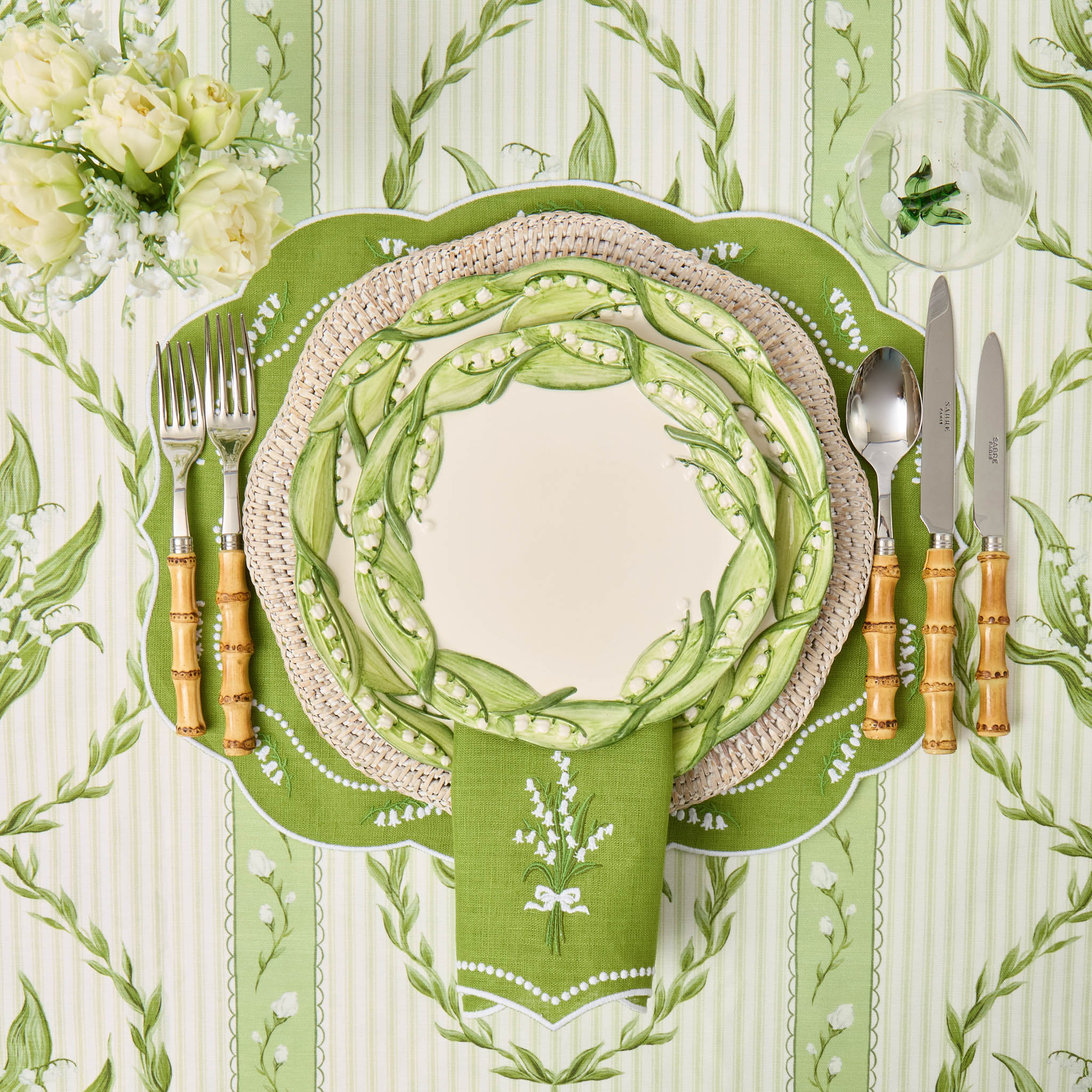 Green place setting with cutlery on a patterned tablecloth