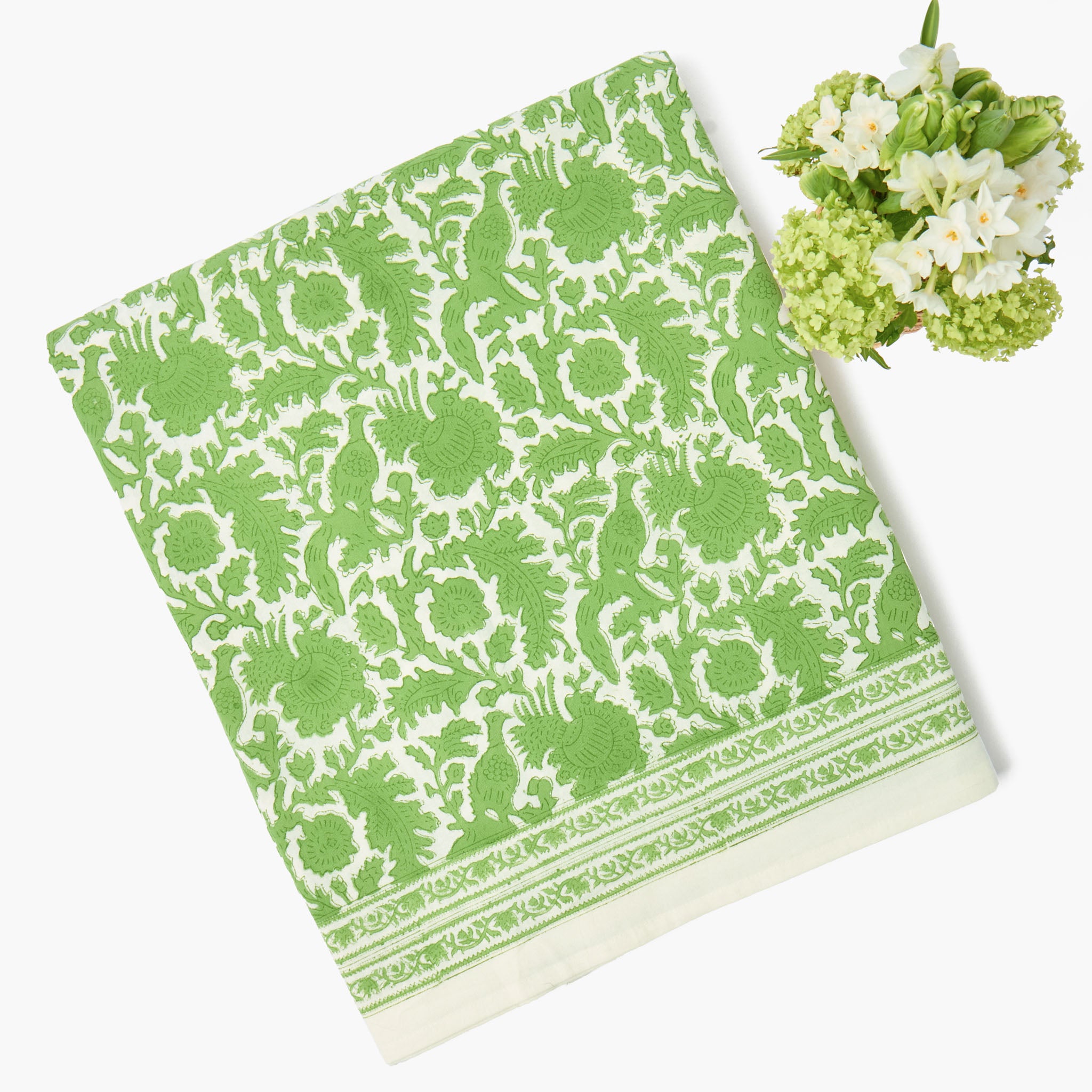Green and white patterned towel with a small bouquet of flowers on a white background