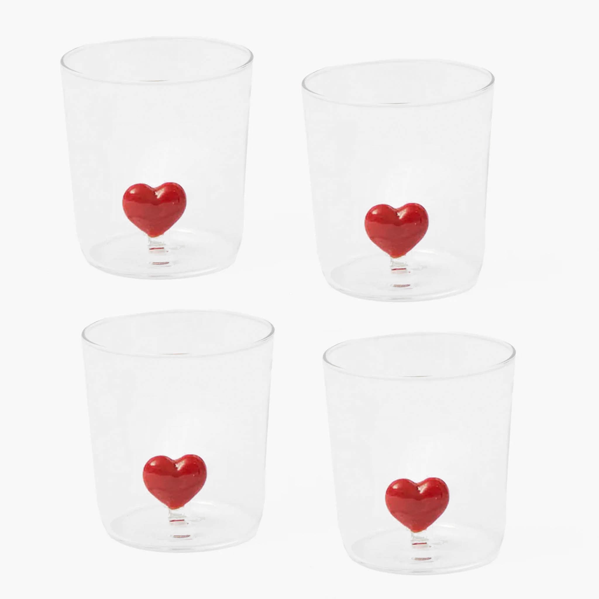 Four clear glasses with red heart designs on a white background