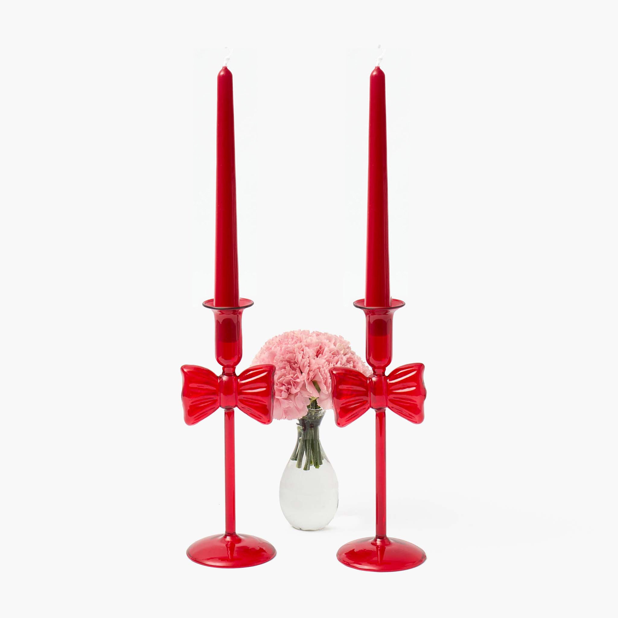 Red bow-shaped candle holders with pink flowers on a white background