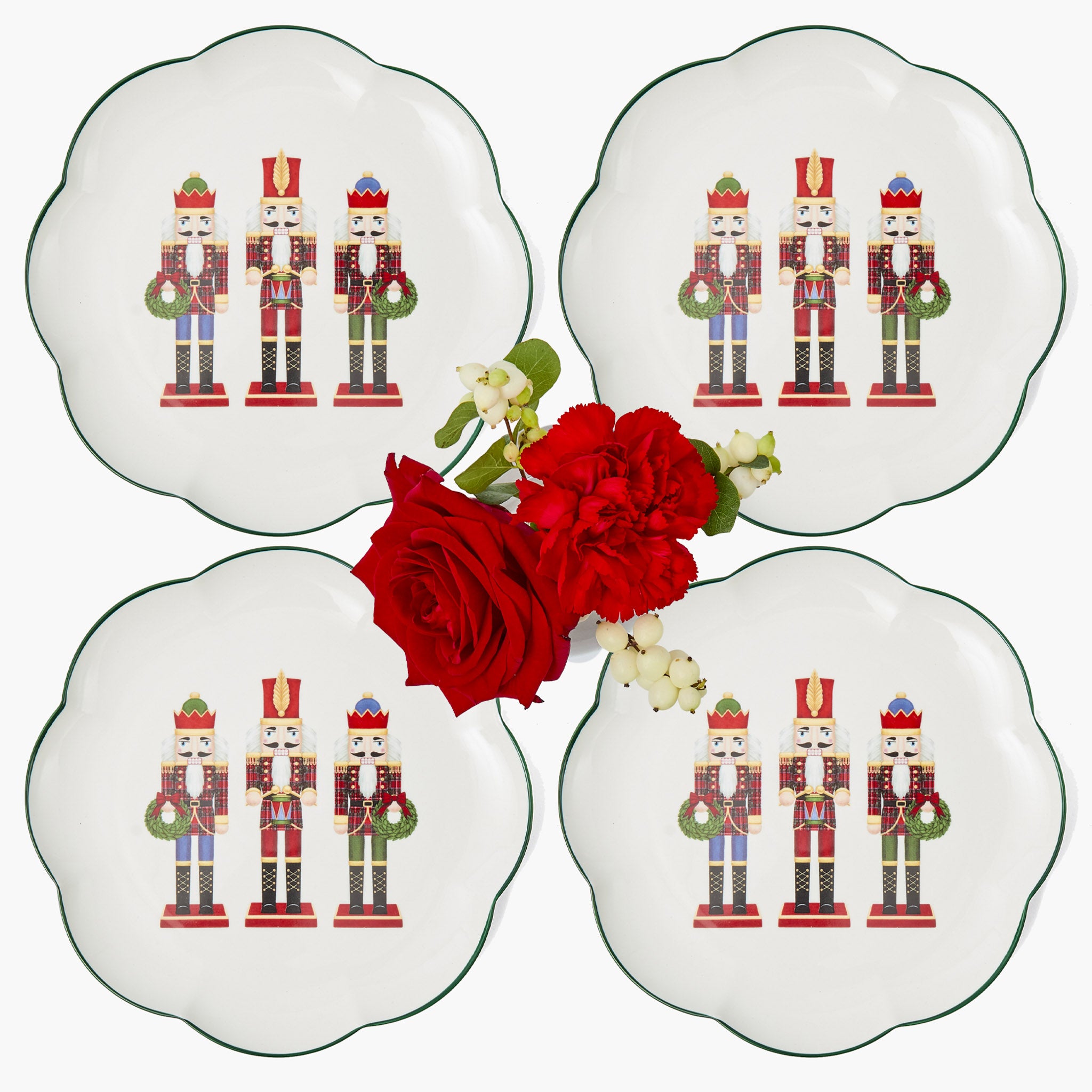 Four decorative plates with nutcracker design and a red rose on a white background