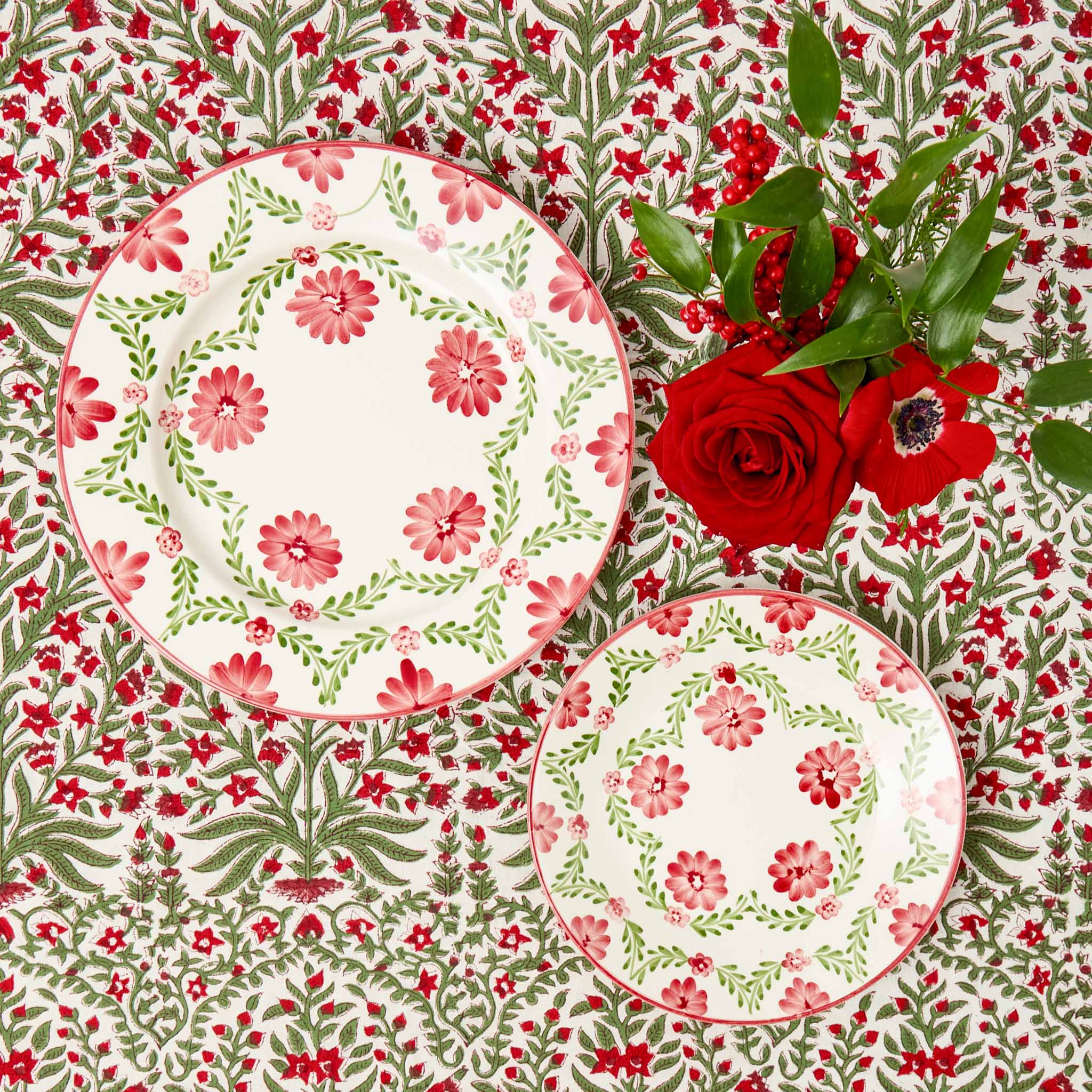 Floral-patterned plates on a matching tablecloth with red roses.