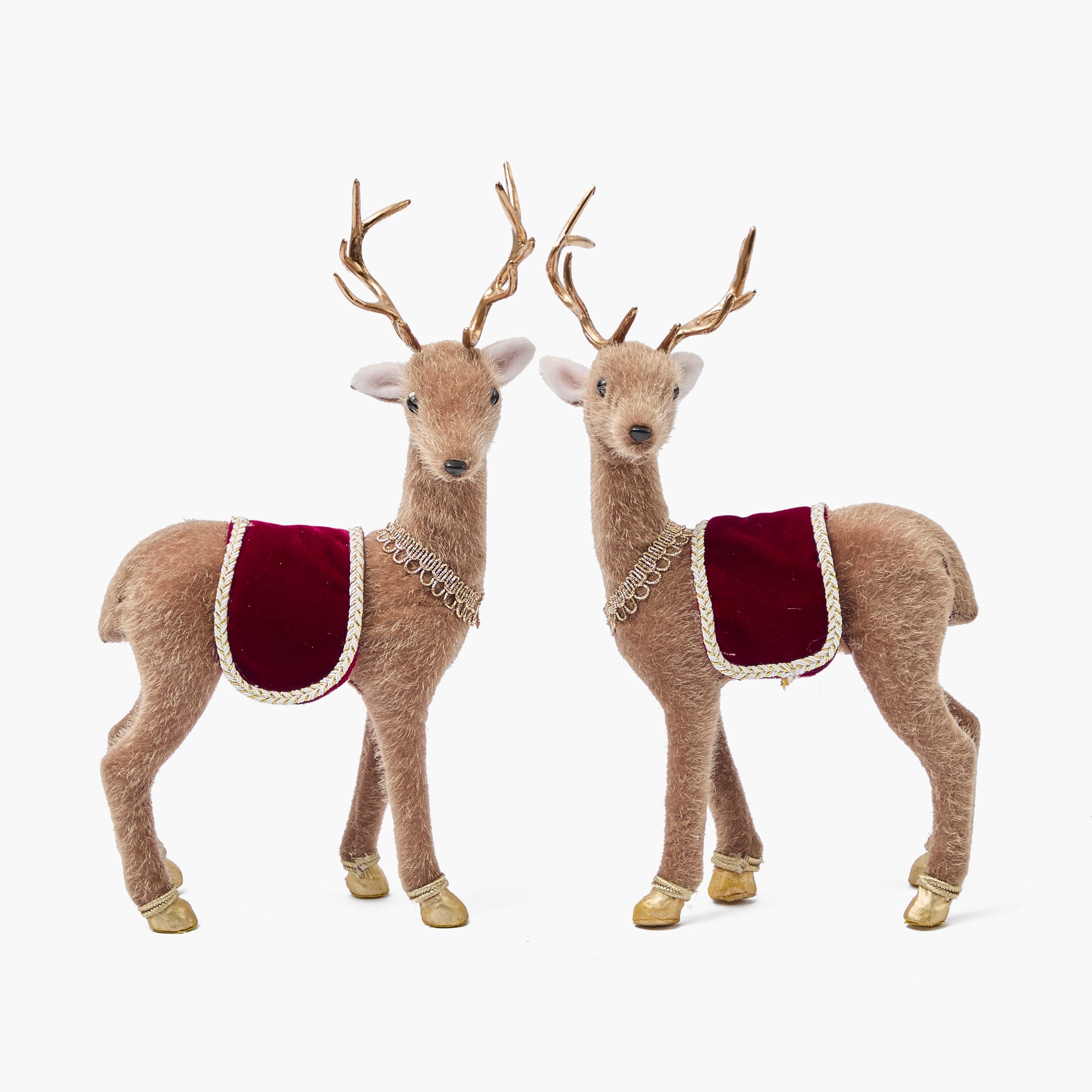 Two decorative deer figurines with red saddle blankets on a white background