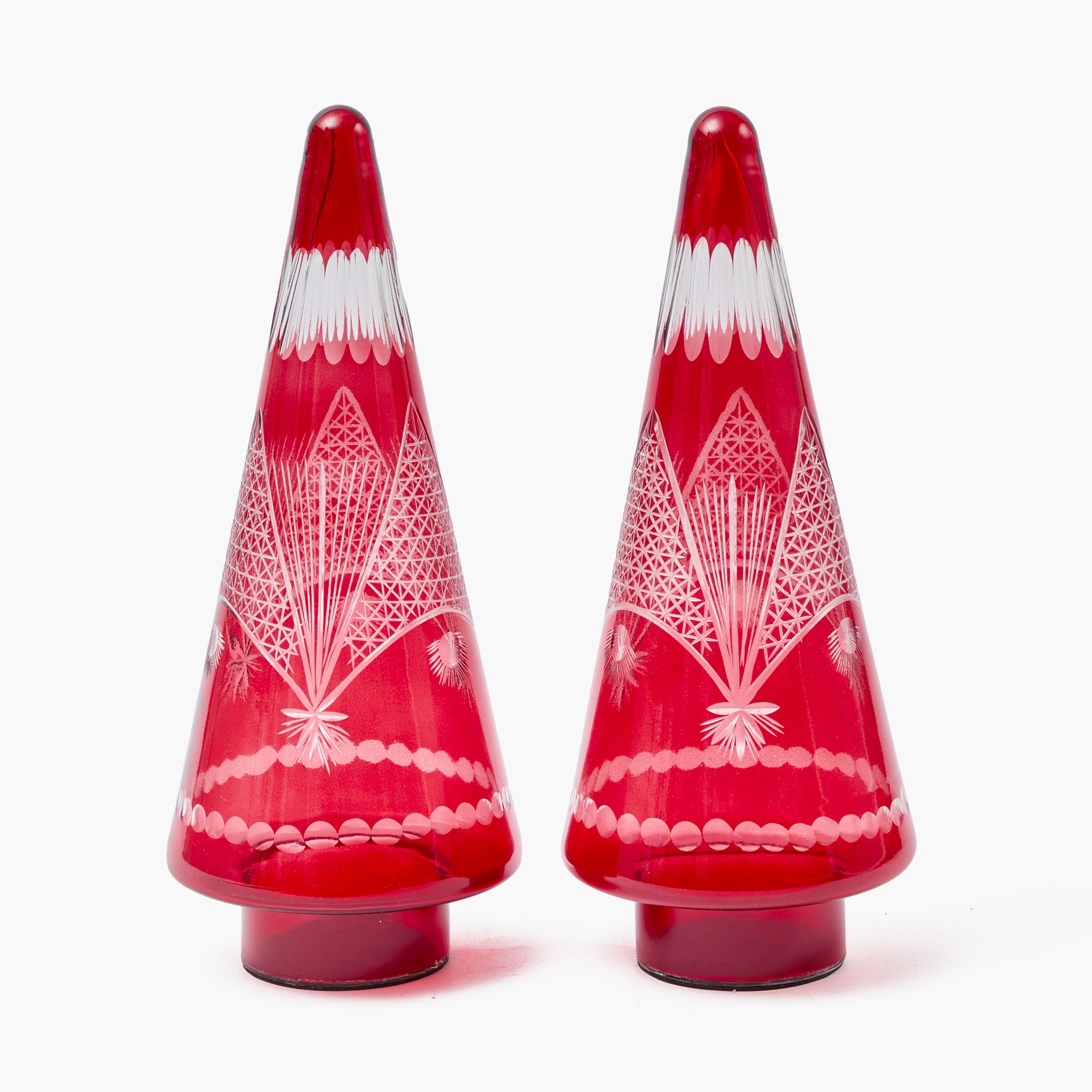 Two red glass Christmas tree ornaments with white geometric patterns on a white background