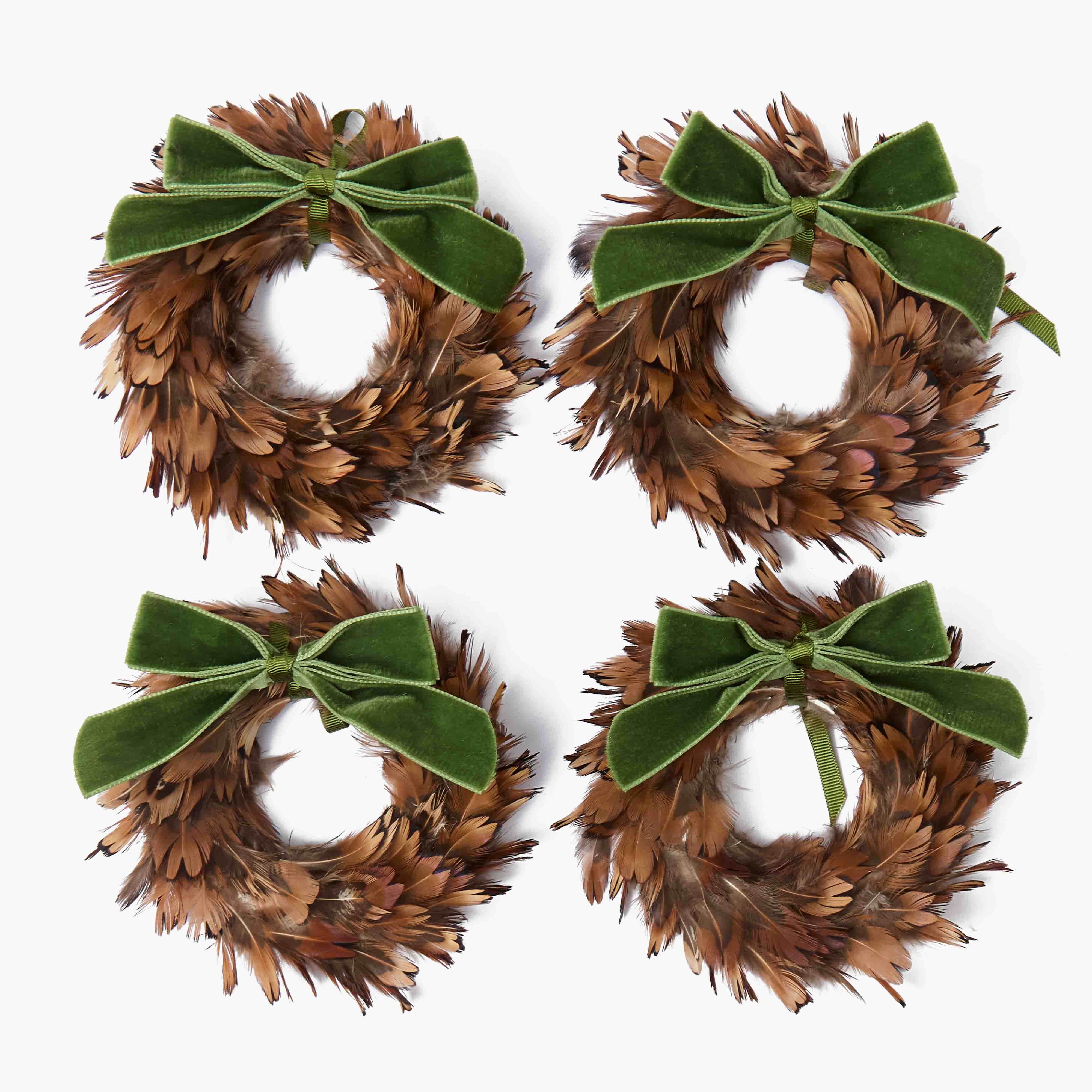 Four feather wreaths with green velvet bows on a white background