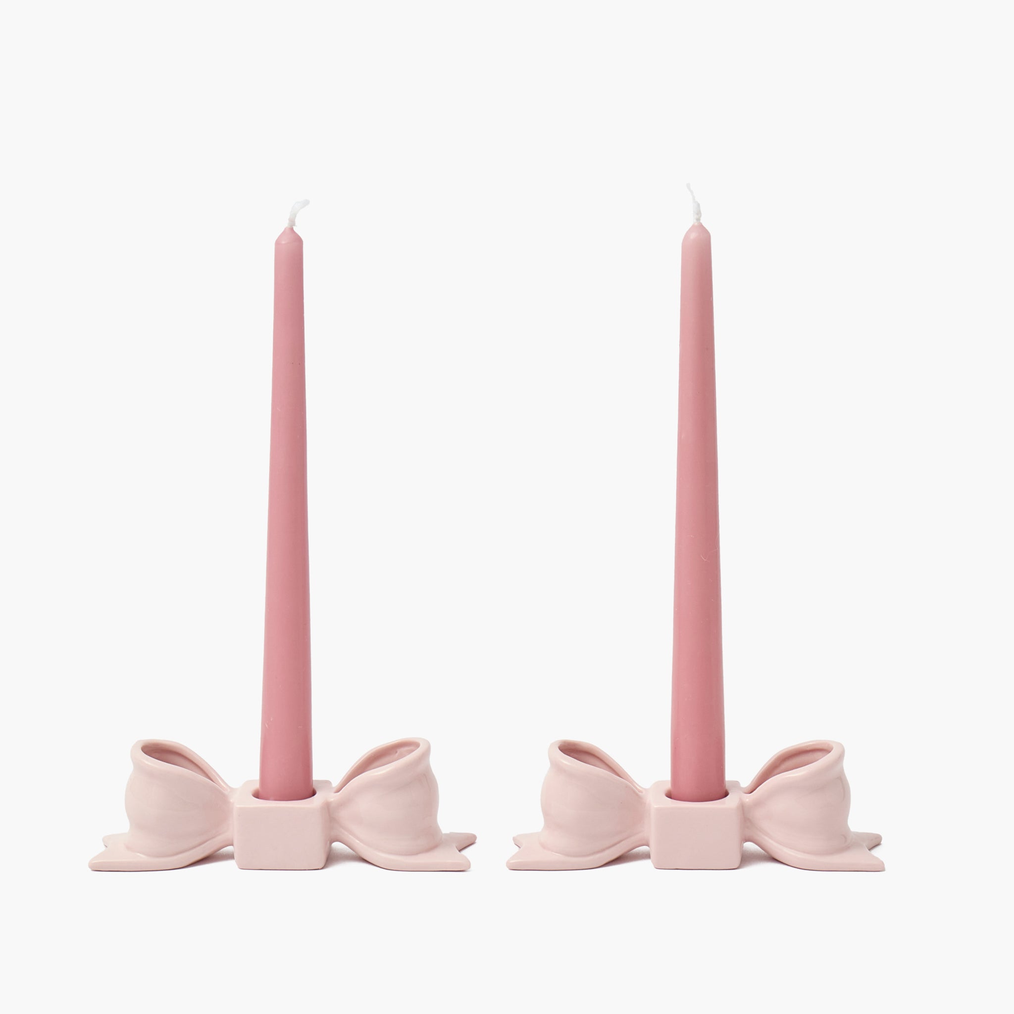 Two pink candle holders with candles on a white background