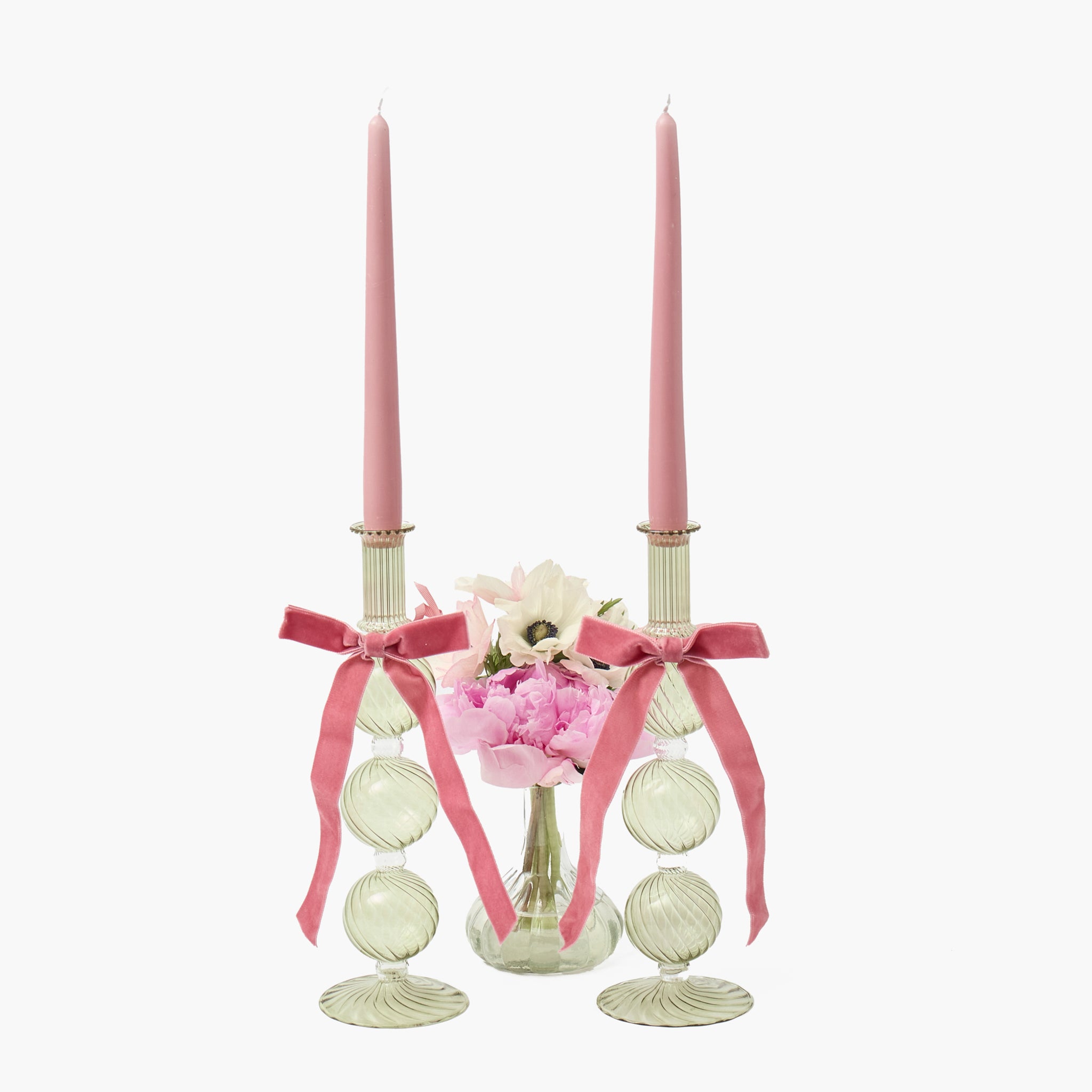 Decorative candle holder with pink candles, ribbons, and flowers on a white background