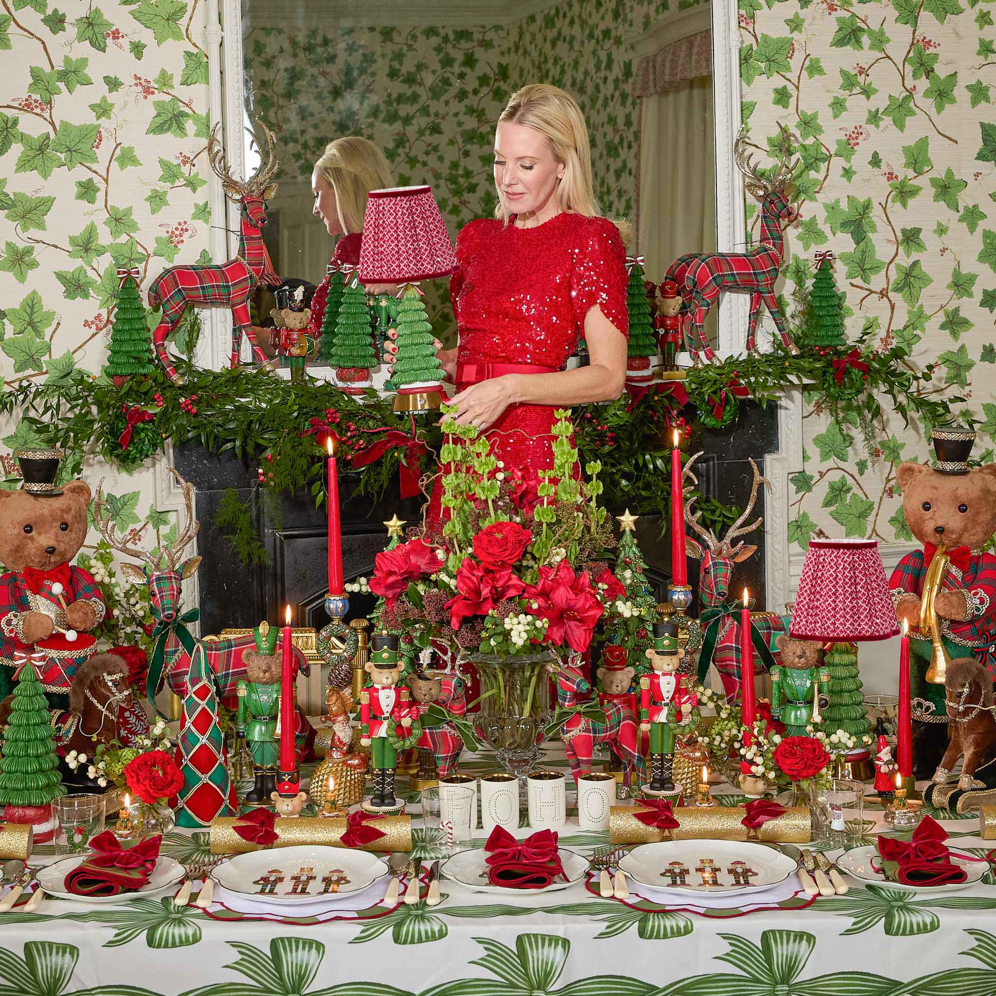 Mrs Alice in a red dress standing in a festively decorated room with Christmas decorations.
