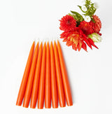 Set of 8 artisanal handmade candles in vibrant orange.