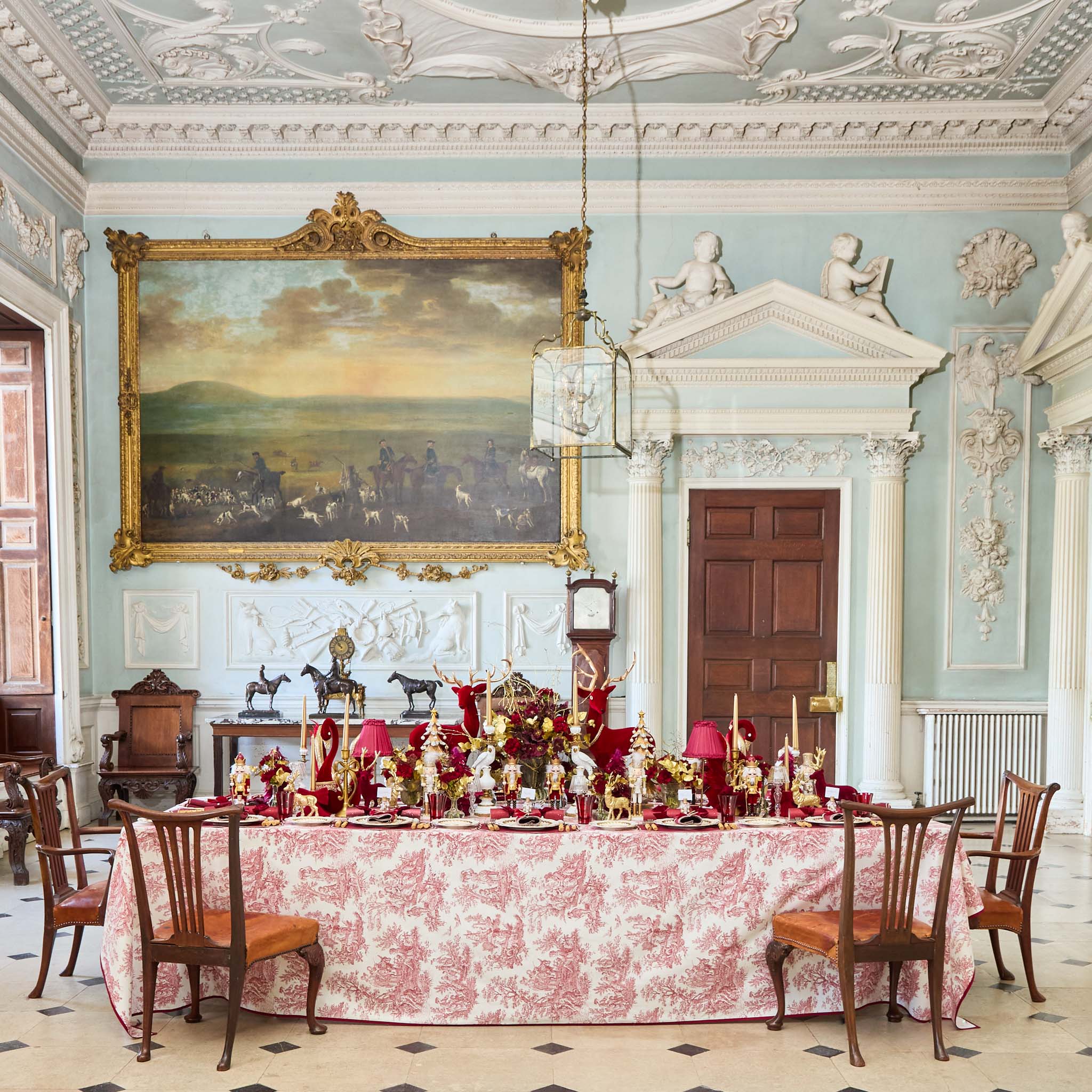 Dining room with ornate decor, including a large painting on the wall and a decorated table.