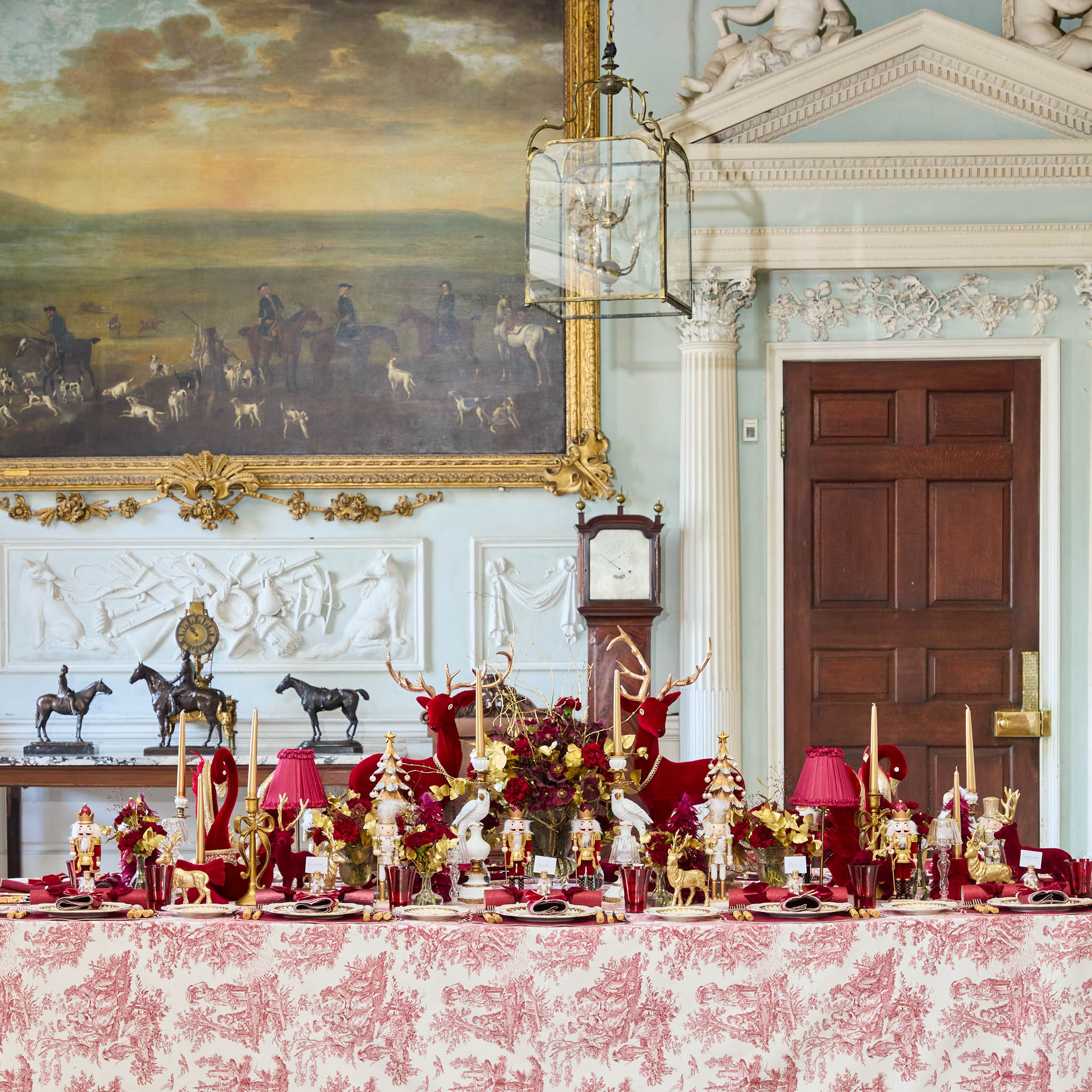 Decorative table setting in an elegant room with a large painting and wooden door.
