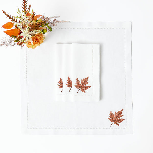 Set of 4 napkins adorned with autumn leaf motifs on white linen.