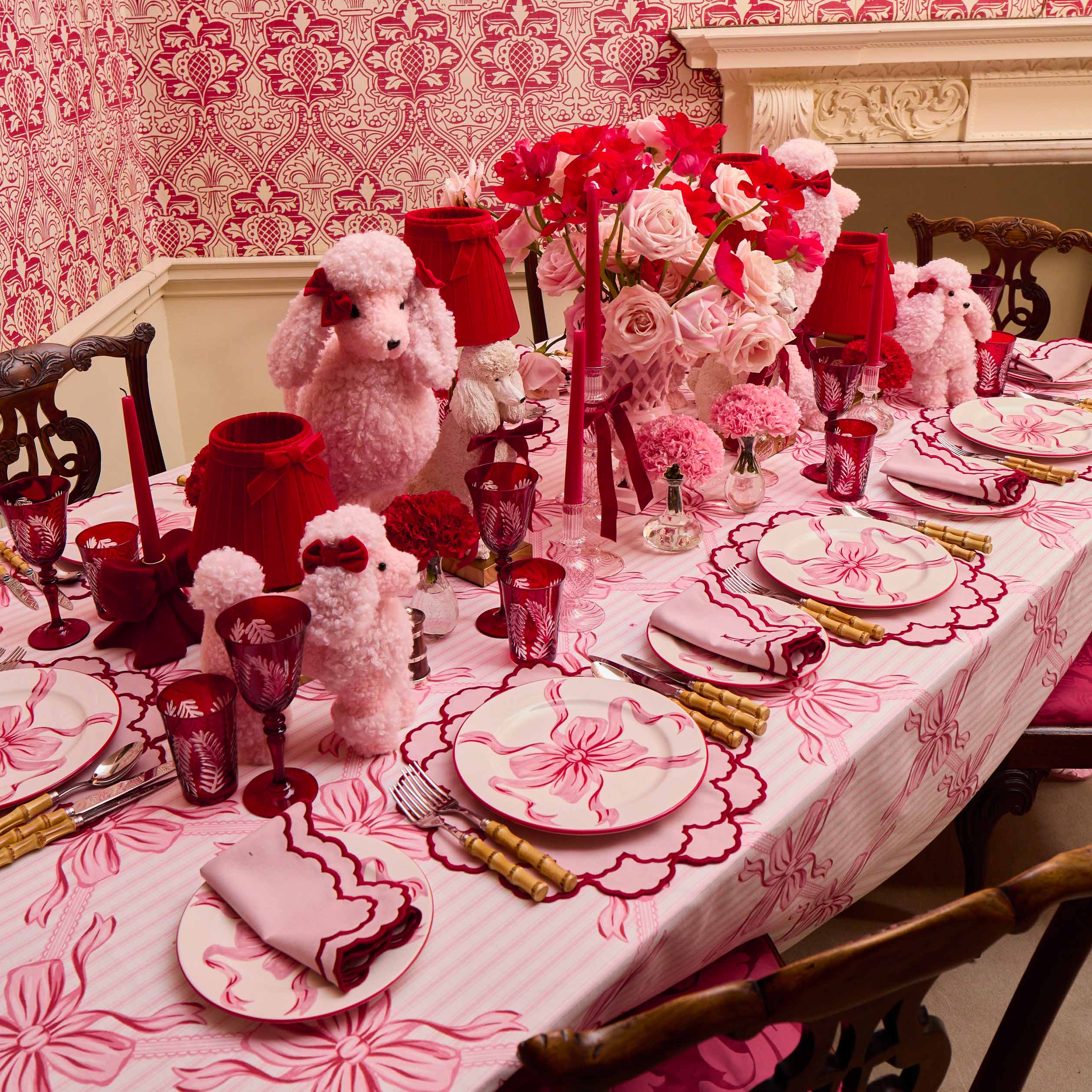 Decorative table setting with pink and red theme, including flowers and teddy bears.