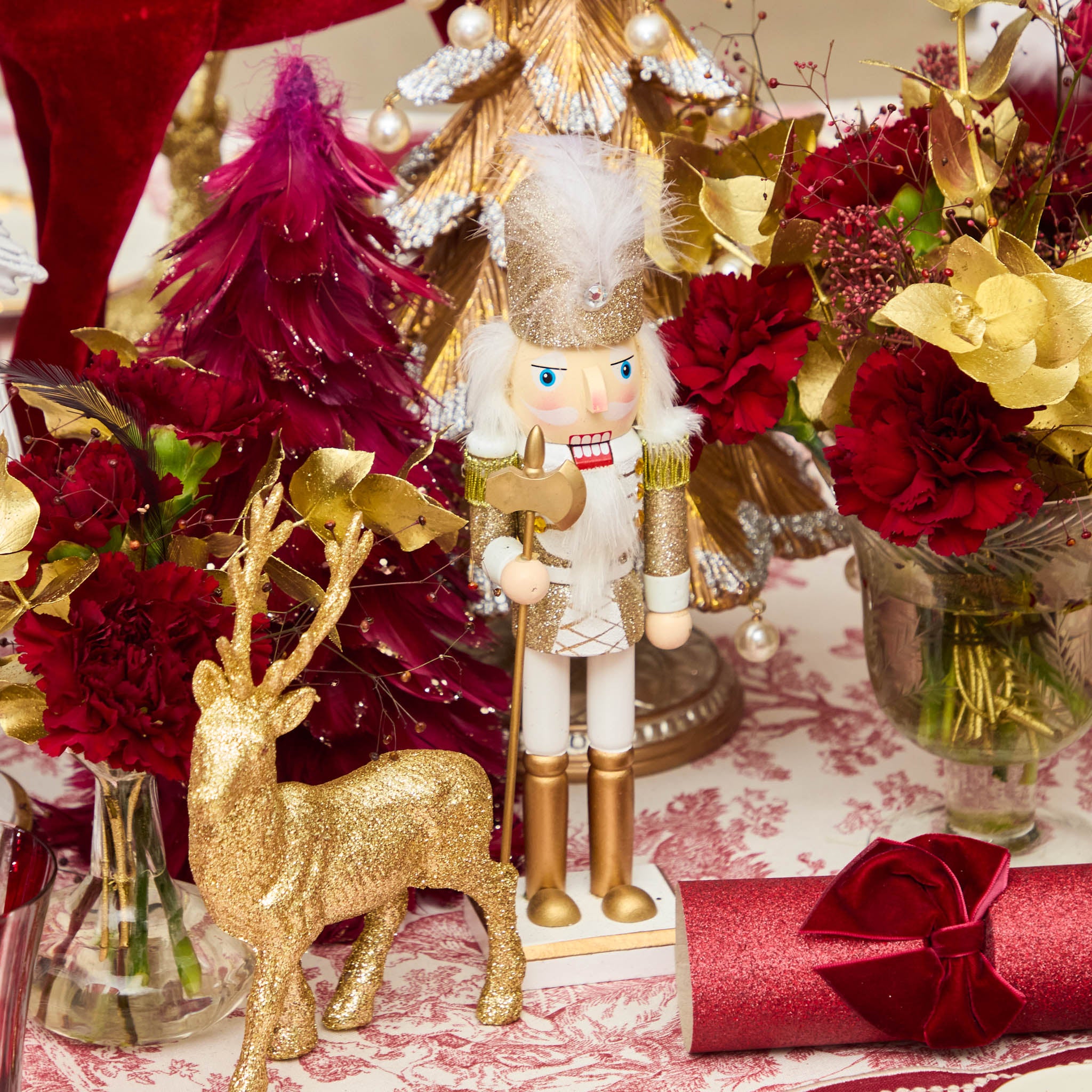 Decorative Christmas table setting with nutcracker, deer, and floral arrangements.