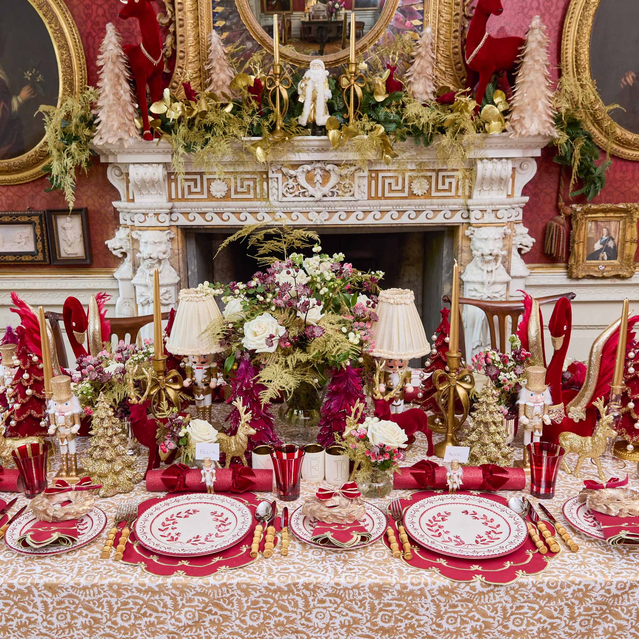 Decorative Christmas table setting with red and gold theme in a richly decorated room.