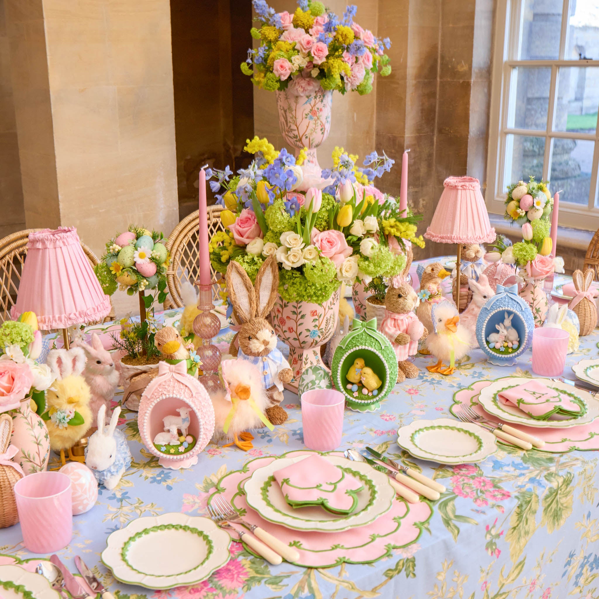 Easter-themed table setting with floral arrangements, bunny figurines, and pastel colors.