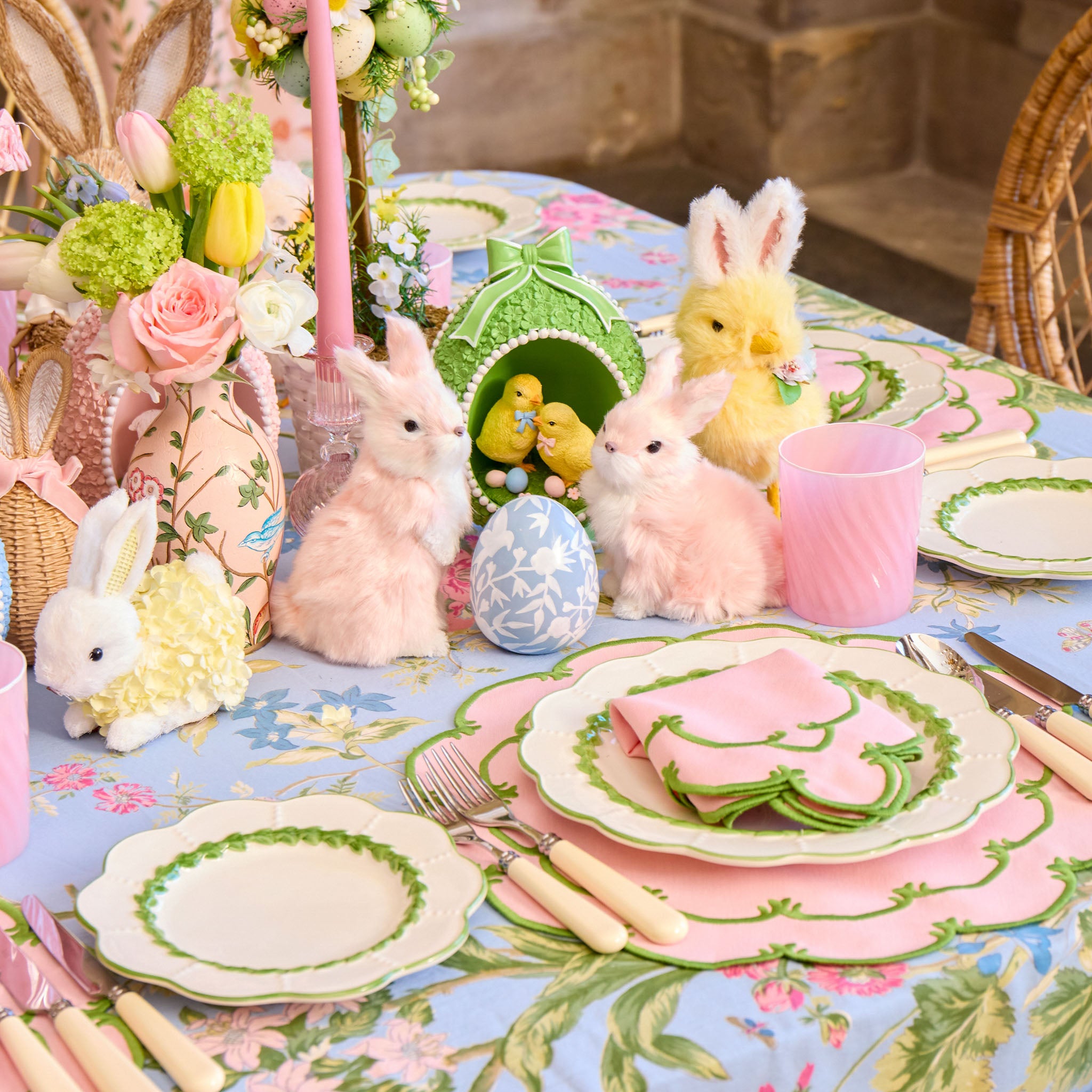 Easter-themed table setting with decorative bunnies, eggs, and a floral tablecloth.