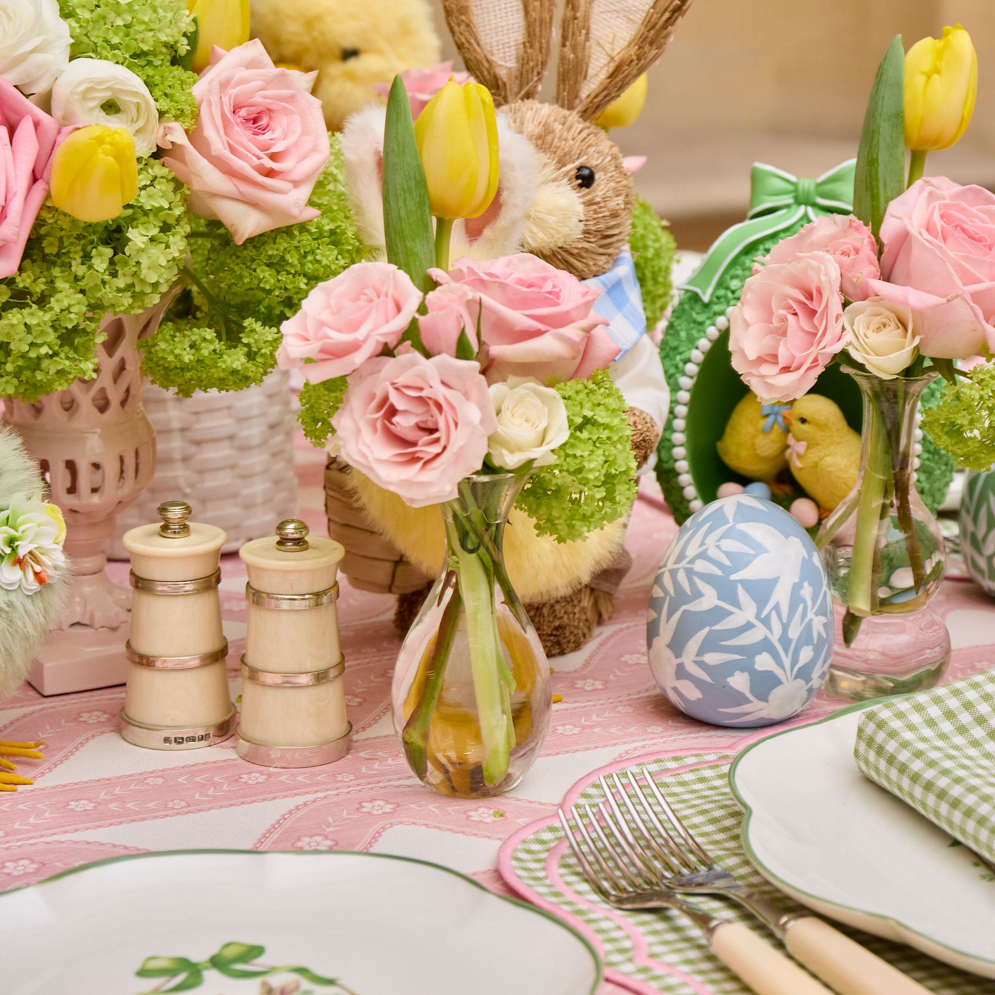 Easter table setting with flowers, eggs, and a bunny figurine.