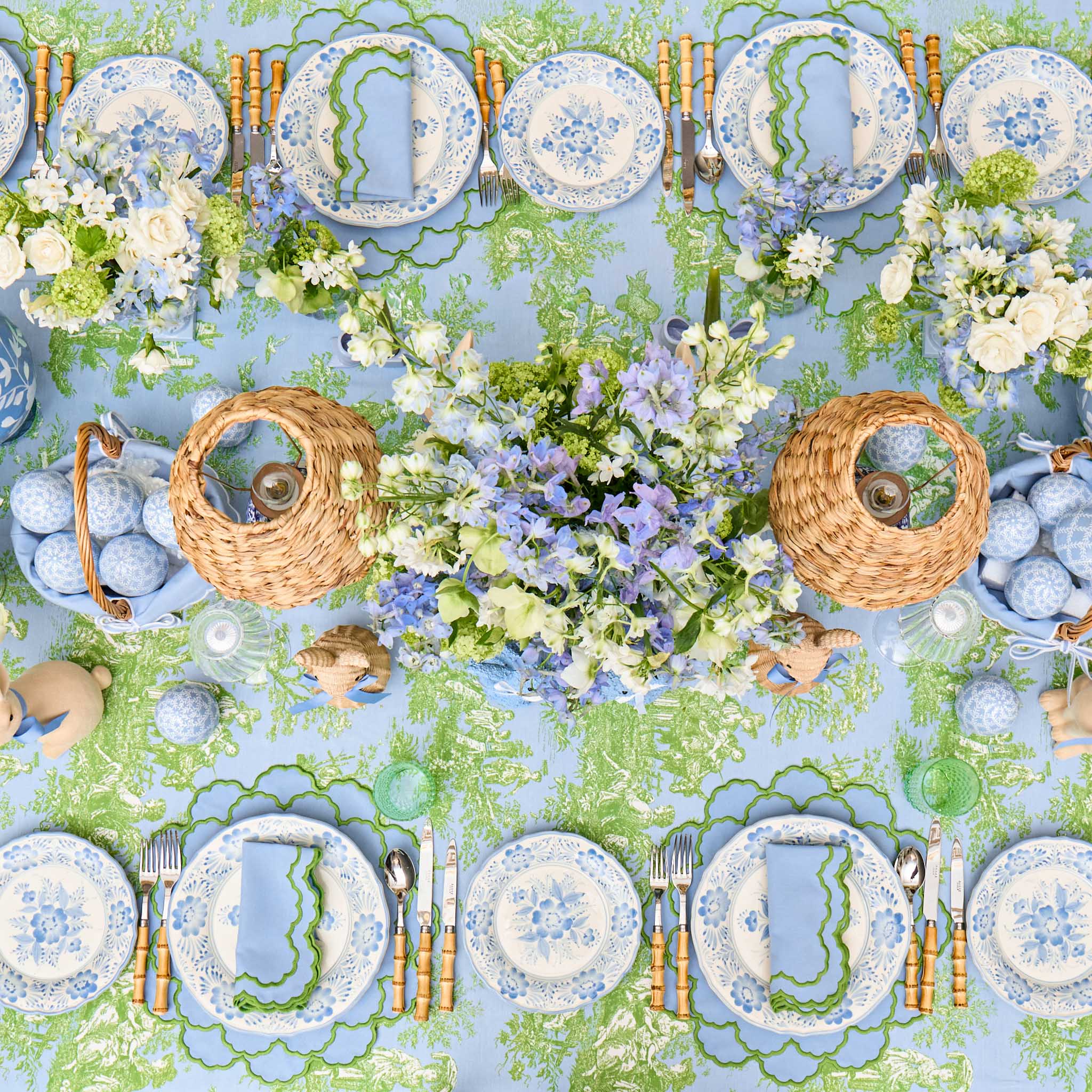 Elegant table setting with floral arrangements, plates, and cutlery on a decorative tablecloth.