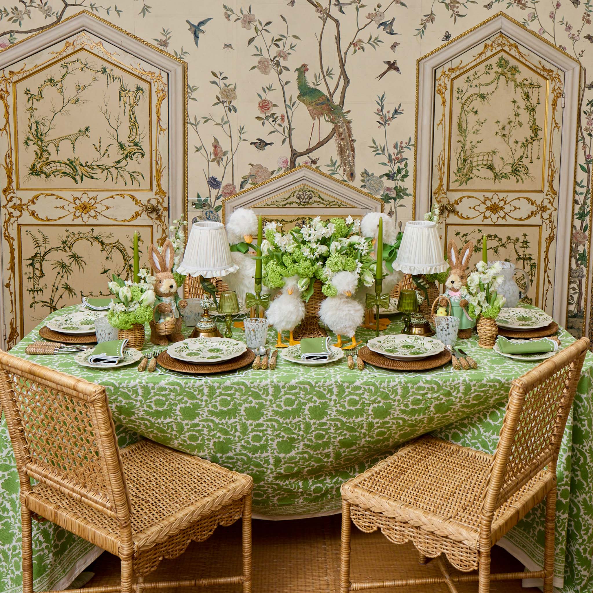 Dining room with a table set for a meal, featuring a green patterned tablecloth and decorative elements.