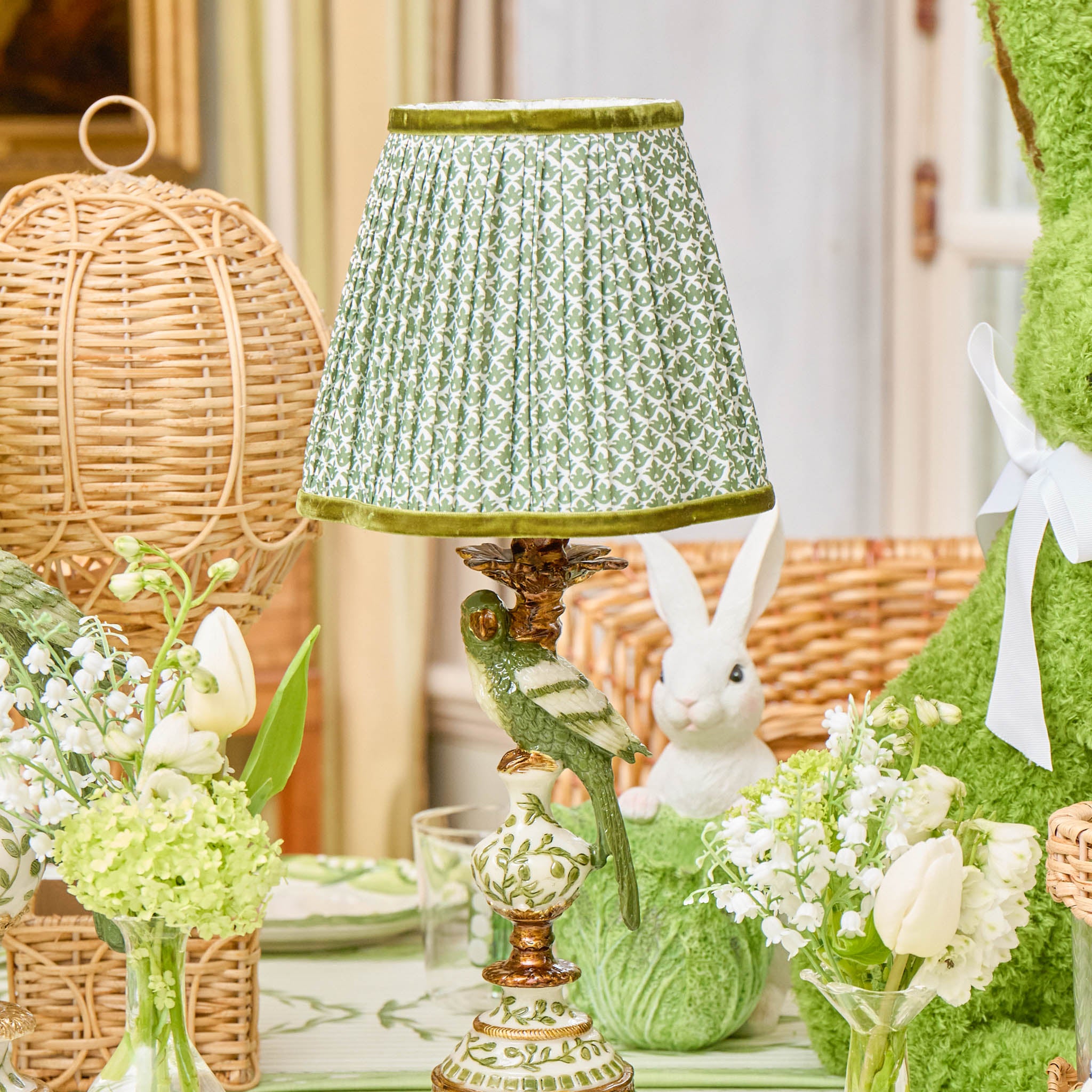 Decorative table setting with a green lamp, flowers, and wicker baskets.