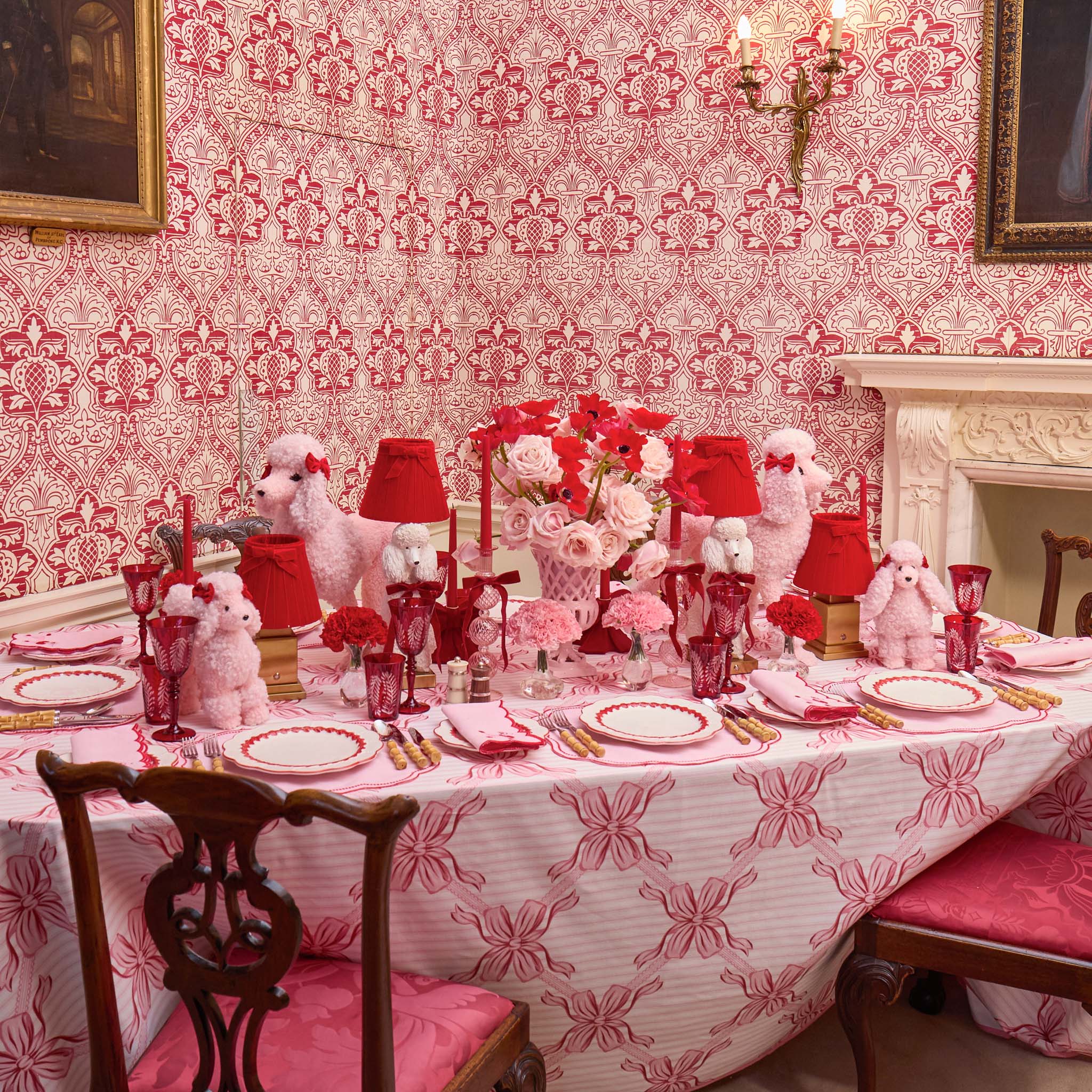 Dining room with a table set for a formal dinner, featuring red and white decor.