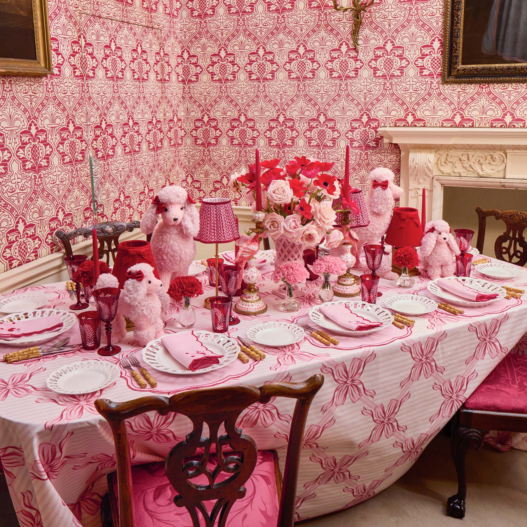 Dining room with a table set for a formal dinner, featuring pink tablecloth and decorative elements.