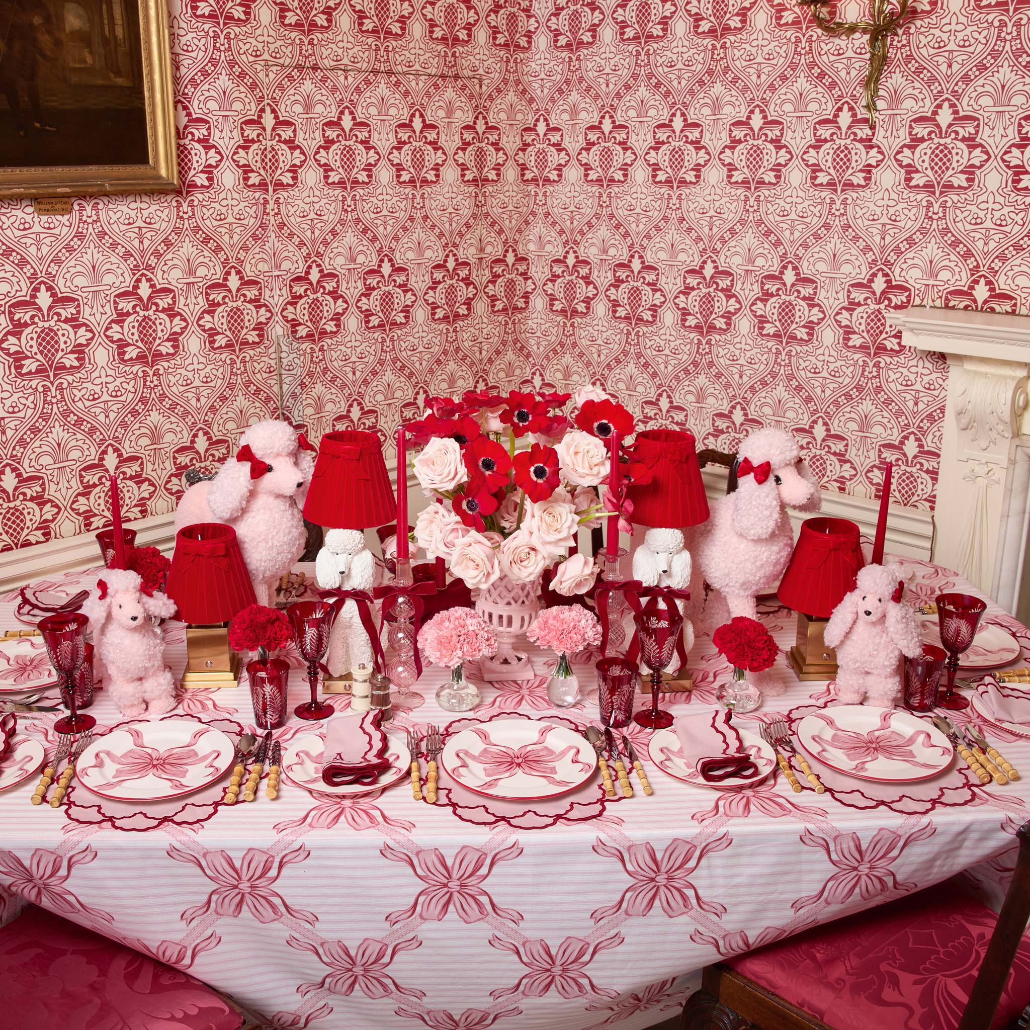 Decorative table setting with red and white theme, including poodle figures and floral arrangements.