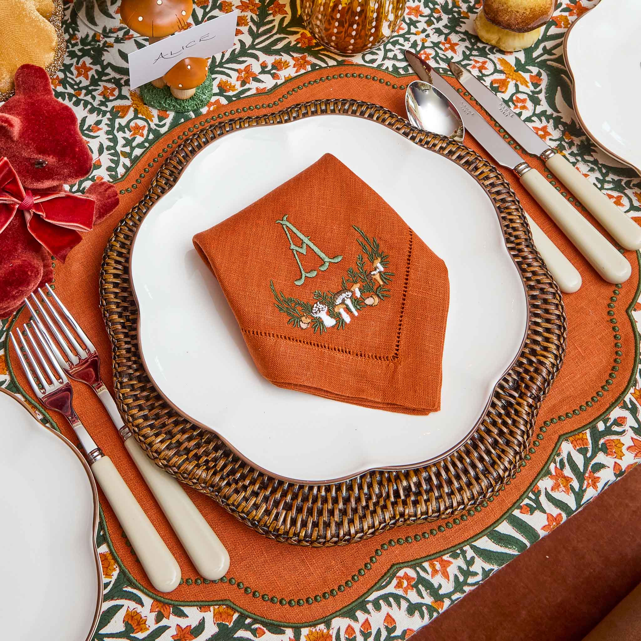 Decorative table setting with an embroidered orange napkin on a table setting.