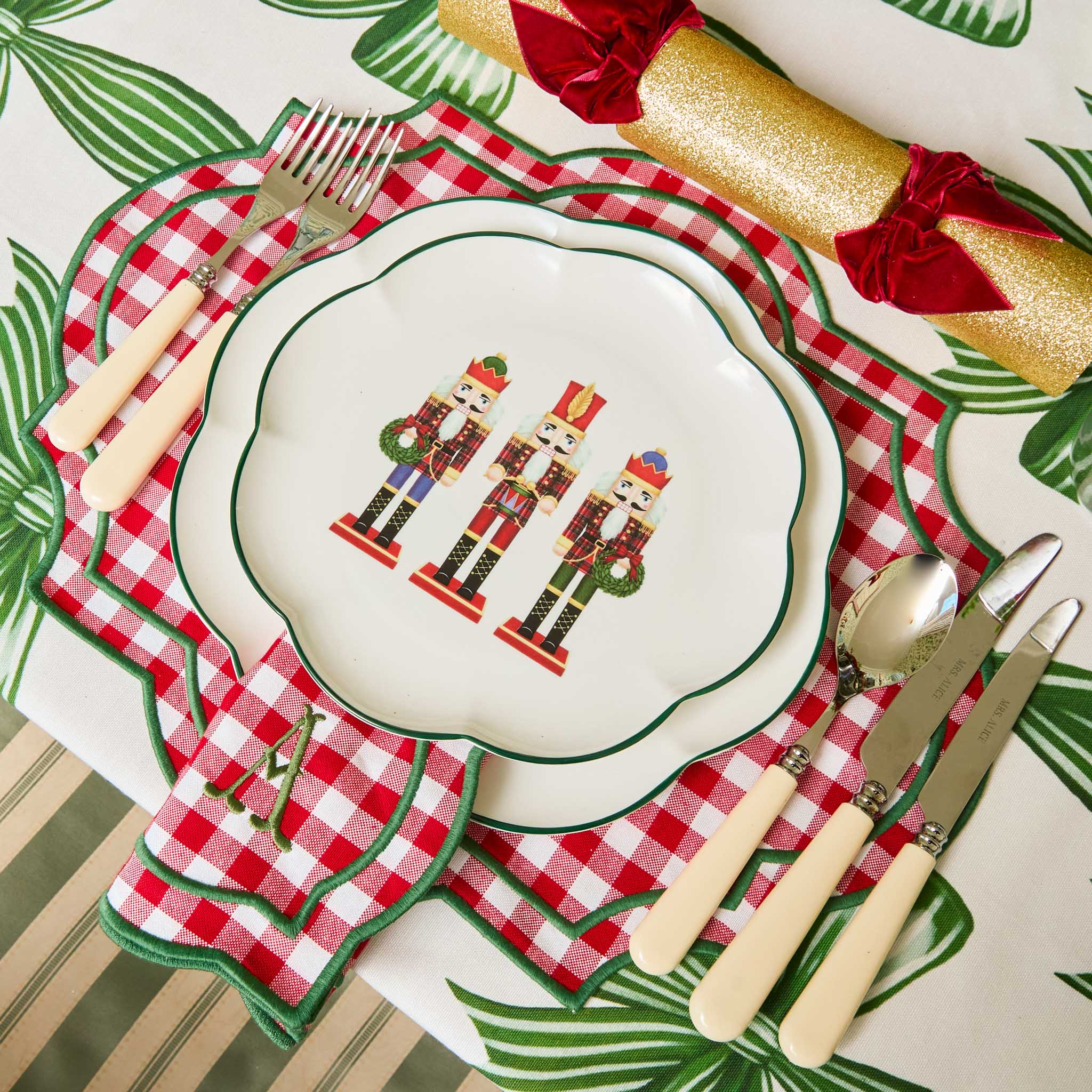 Christmas-themed place setting with nutcrackers on a plate, checkered napkin, and decorative roll of paper.