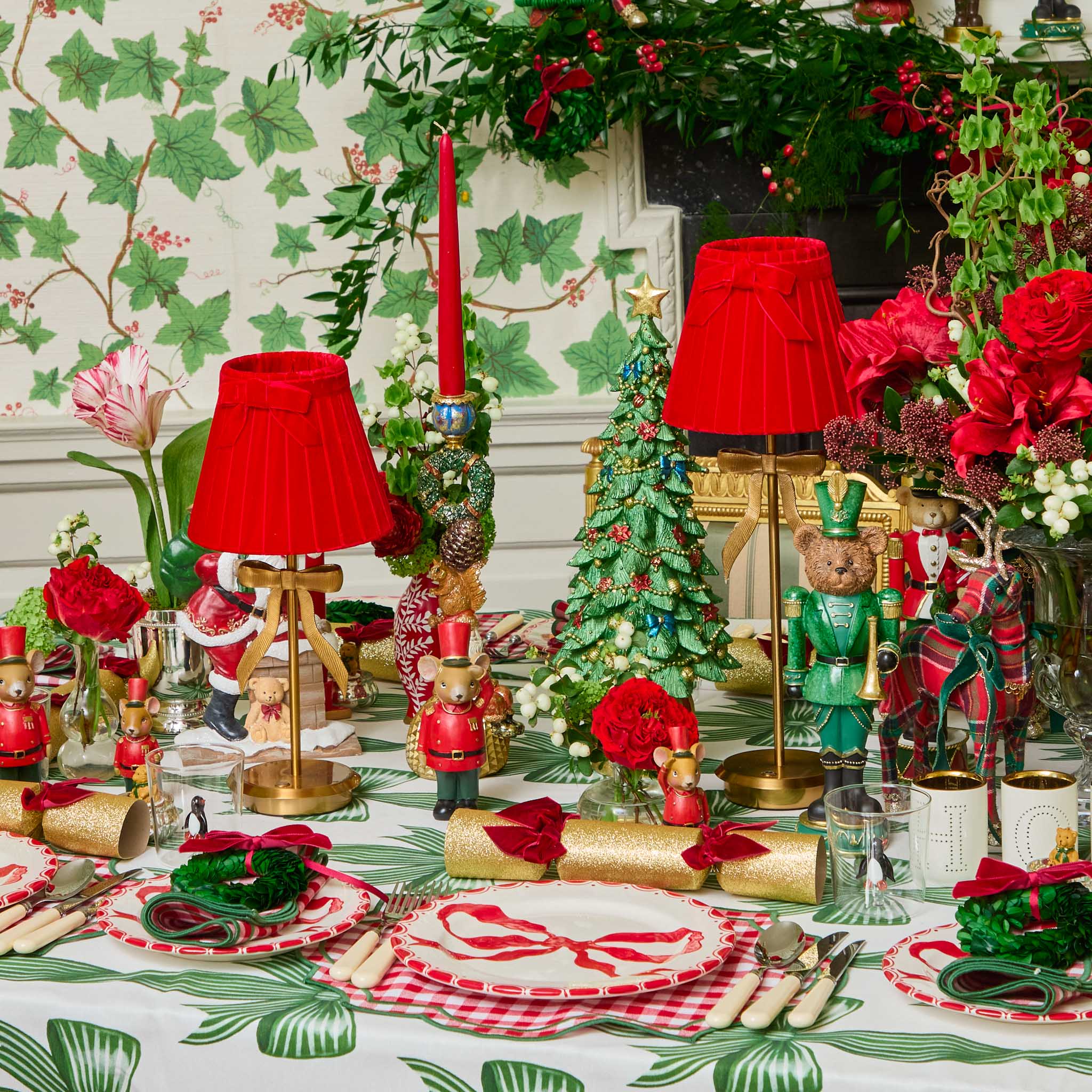 Decorative Christmas table setting with red and green elements, including teddy bears and candles.