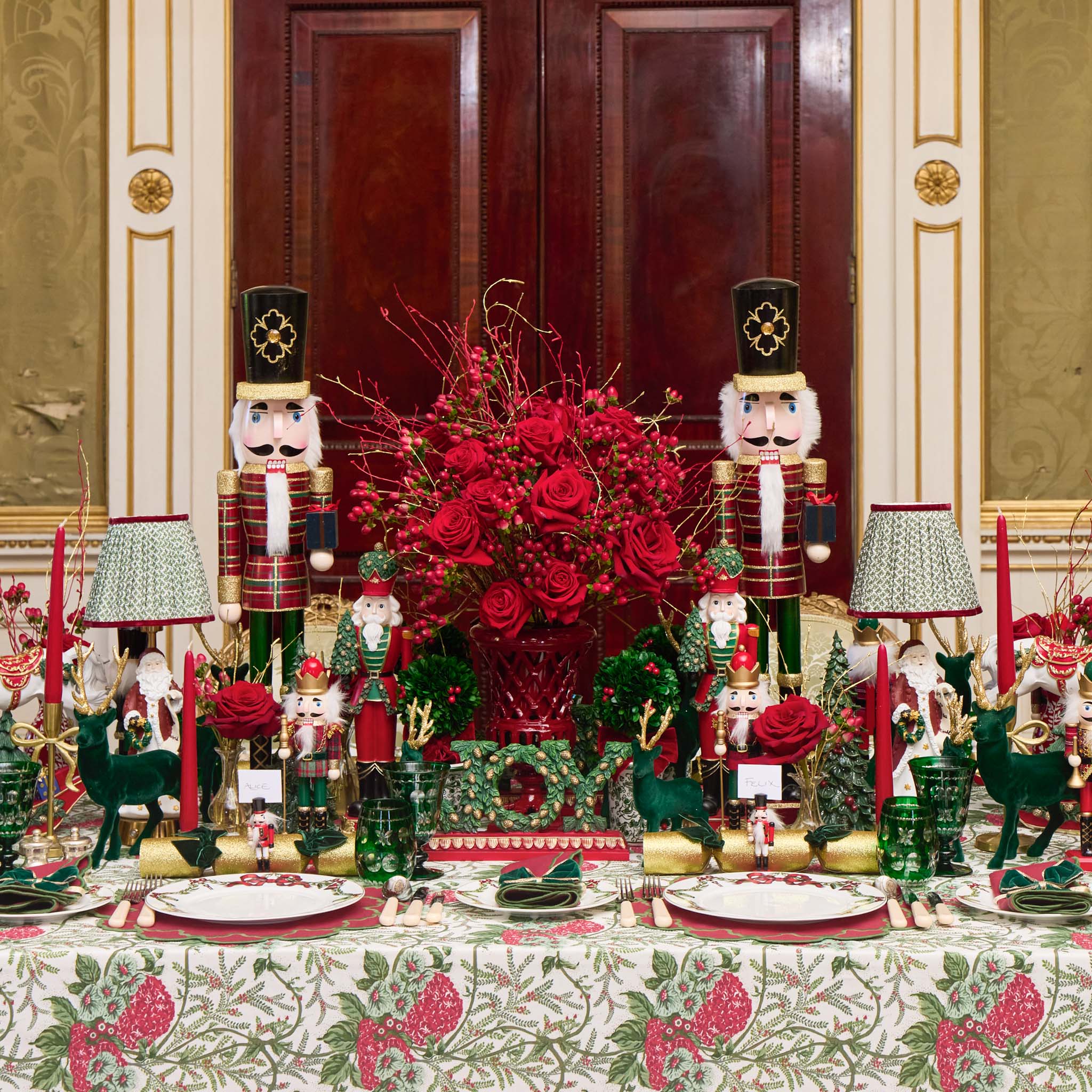 Decorative Christmas table setting with nutcrackers, red flowers, and festive tableware.