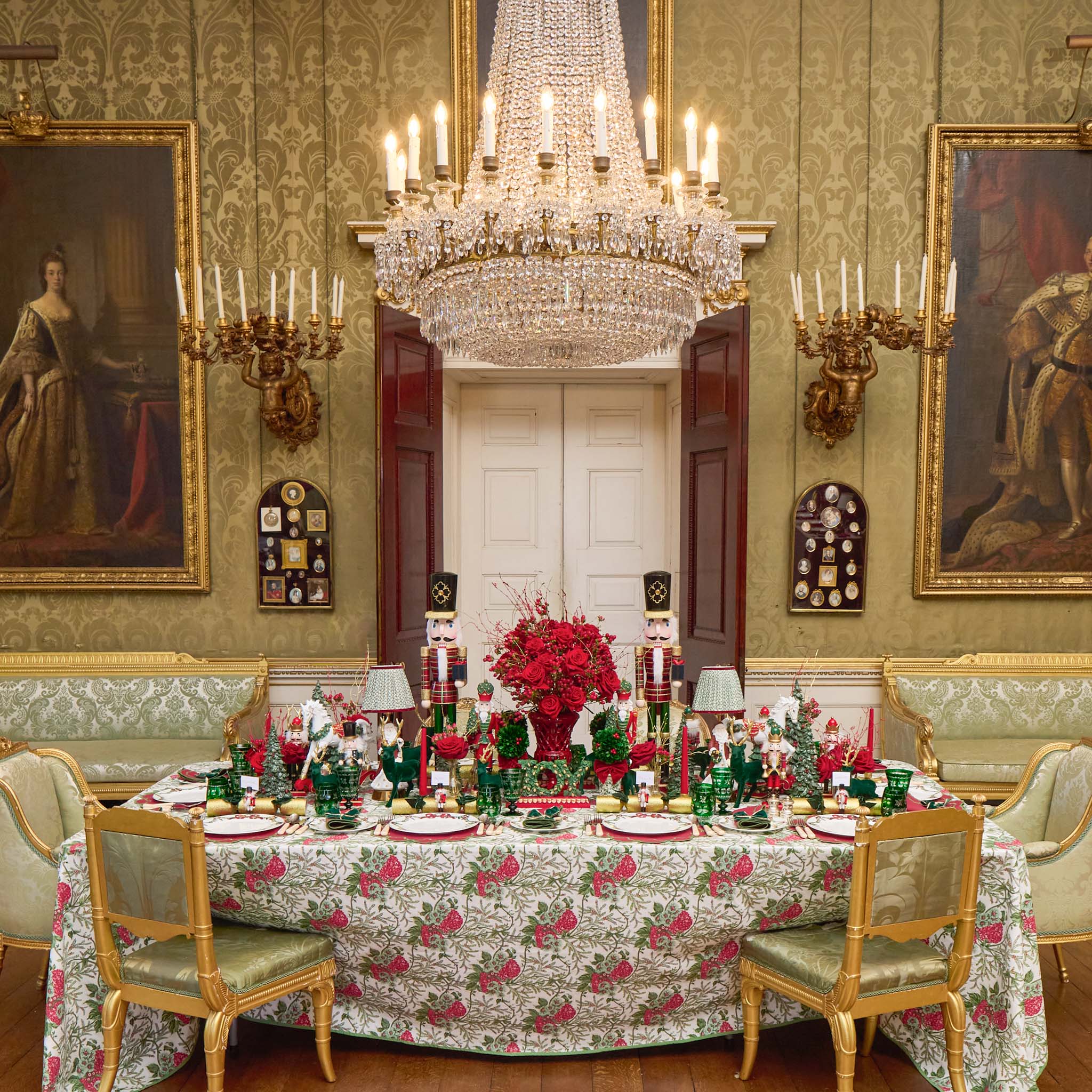 Elegant dining room with a xmas table set for a formal meal, ornate chandelier, and classical decor.