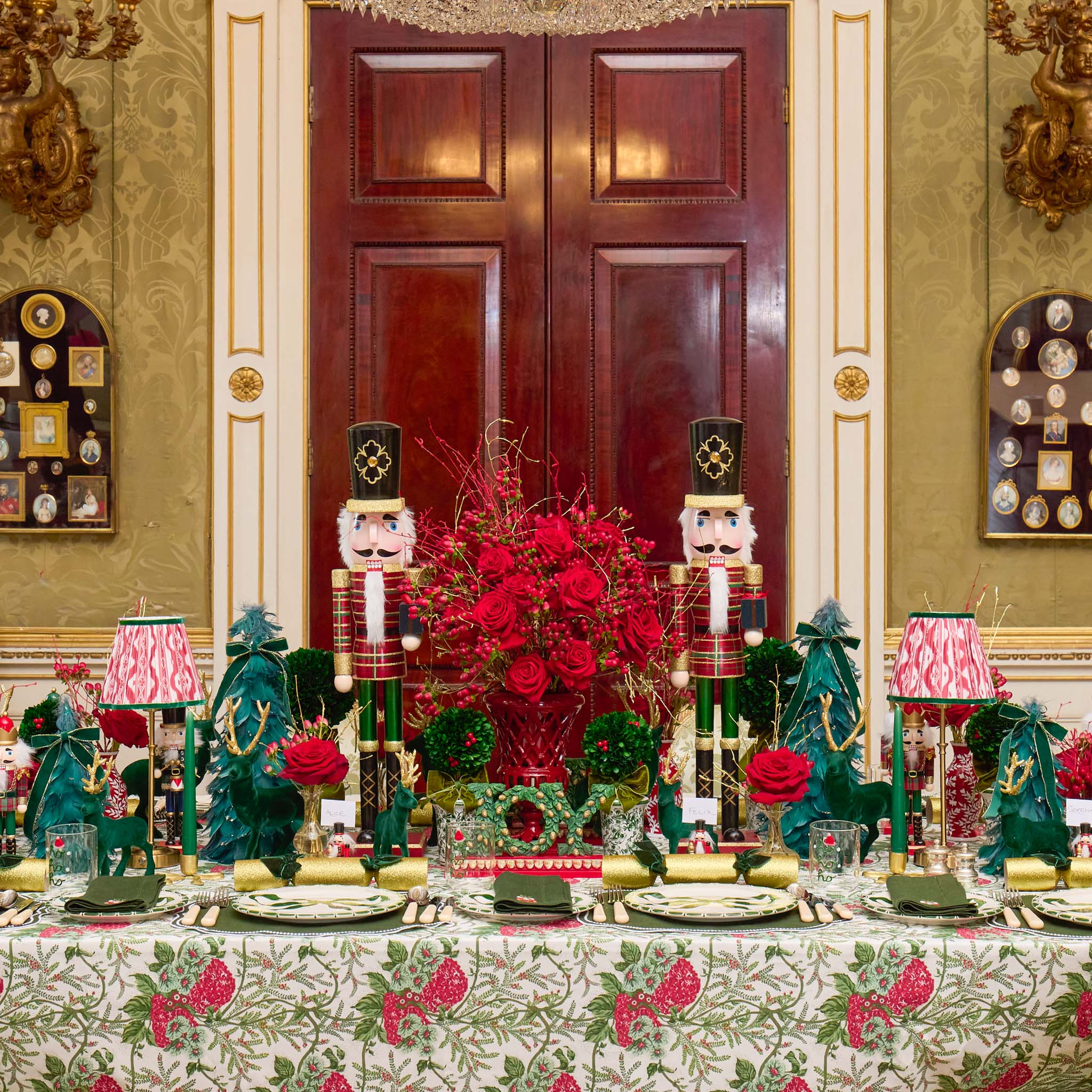 Decorative Christmas table setting with red roses, greenery, and nutcrackers in a formal room.