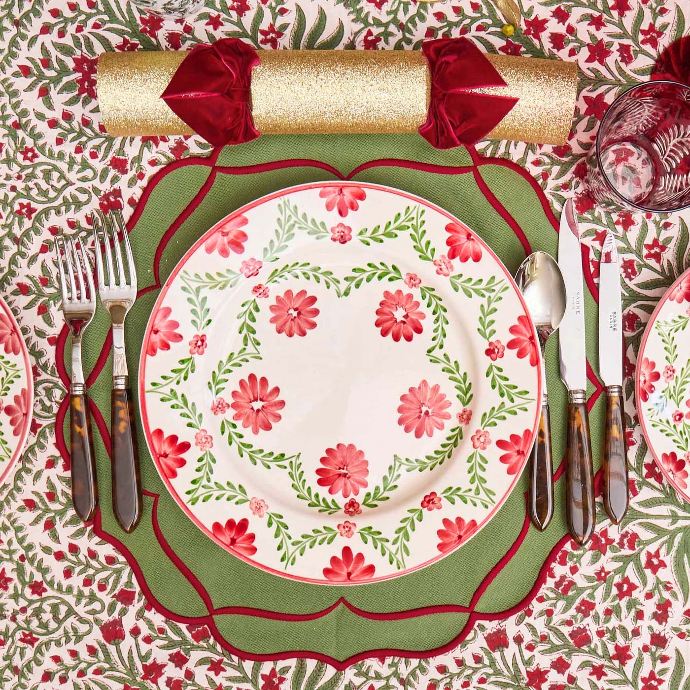 Decorative table setting with floral plates, cutlery, and a patterned tablecloth.