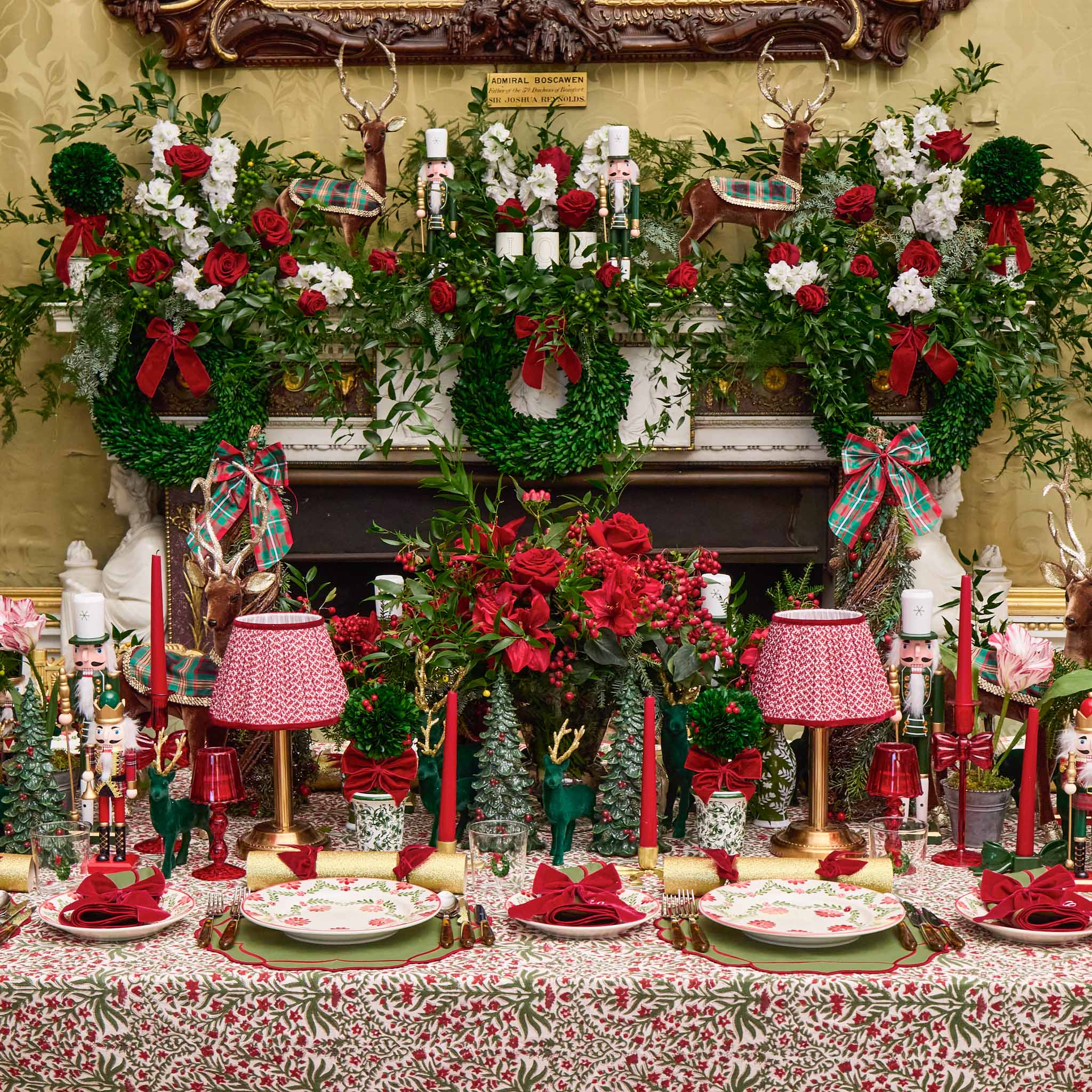 Decorative Christmas table setting with floral arrangements, red candles, and festive decorations.